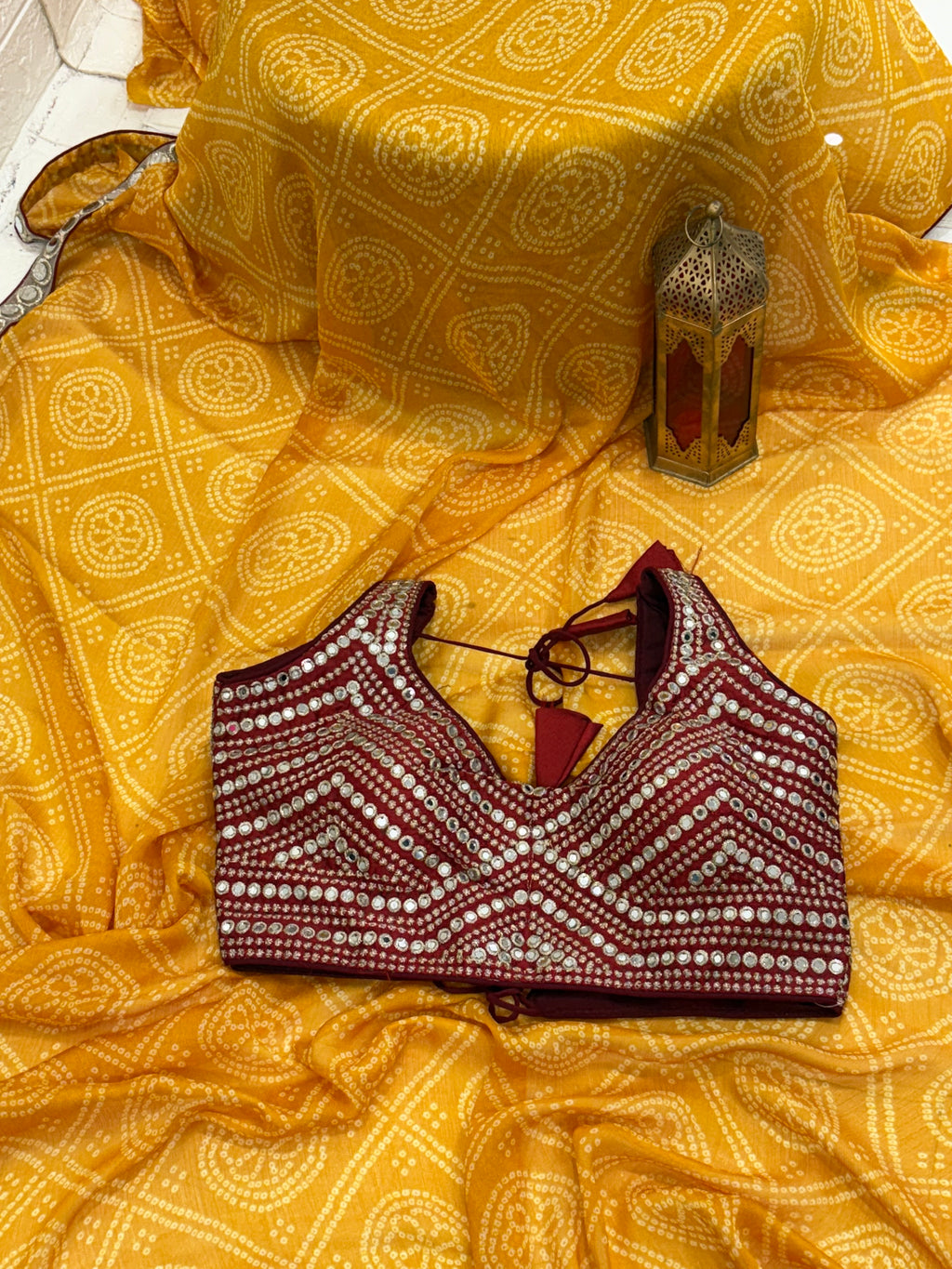 Bandhani print fabric crepe silk yellow colour saree blend with traditional tie-dye pattern and mirror-work maroon blouse embellishment