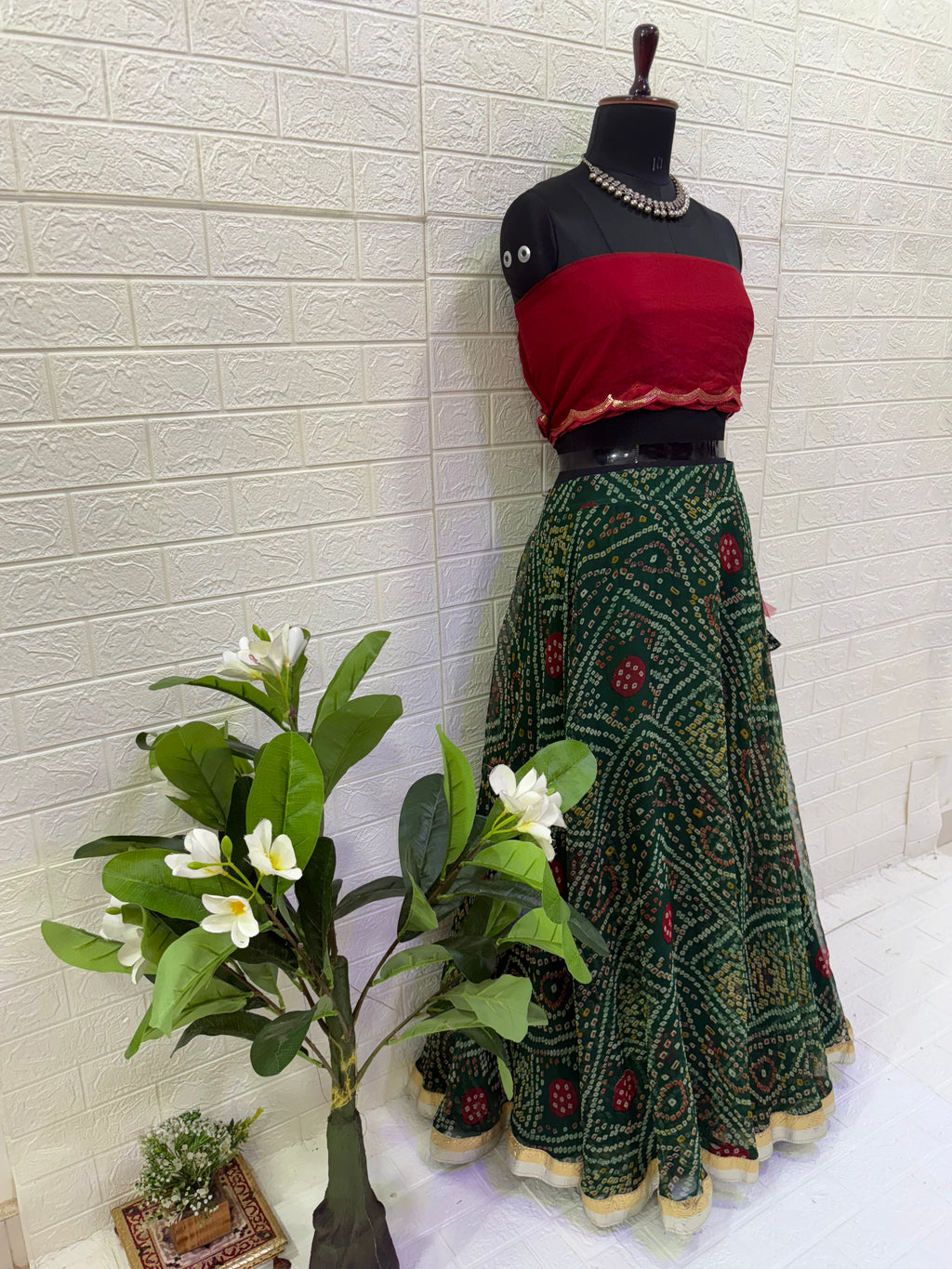 Name:
Emerald Bandhani Lehenga Set Crafted in pure Georgette bandhani print with a deep green flared lehenga and contrast red blouse, finished with golden lace border for a classic festive look.