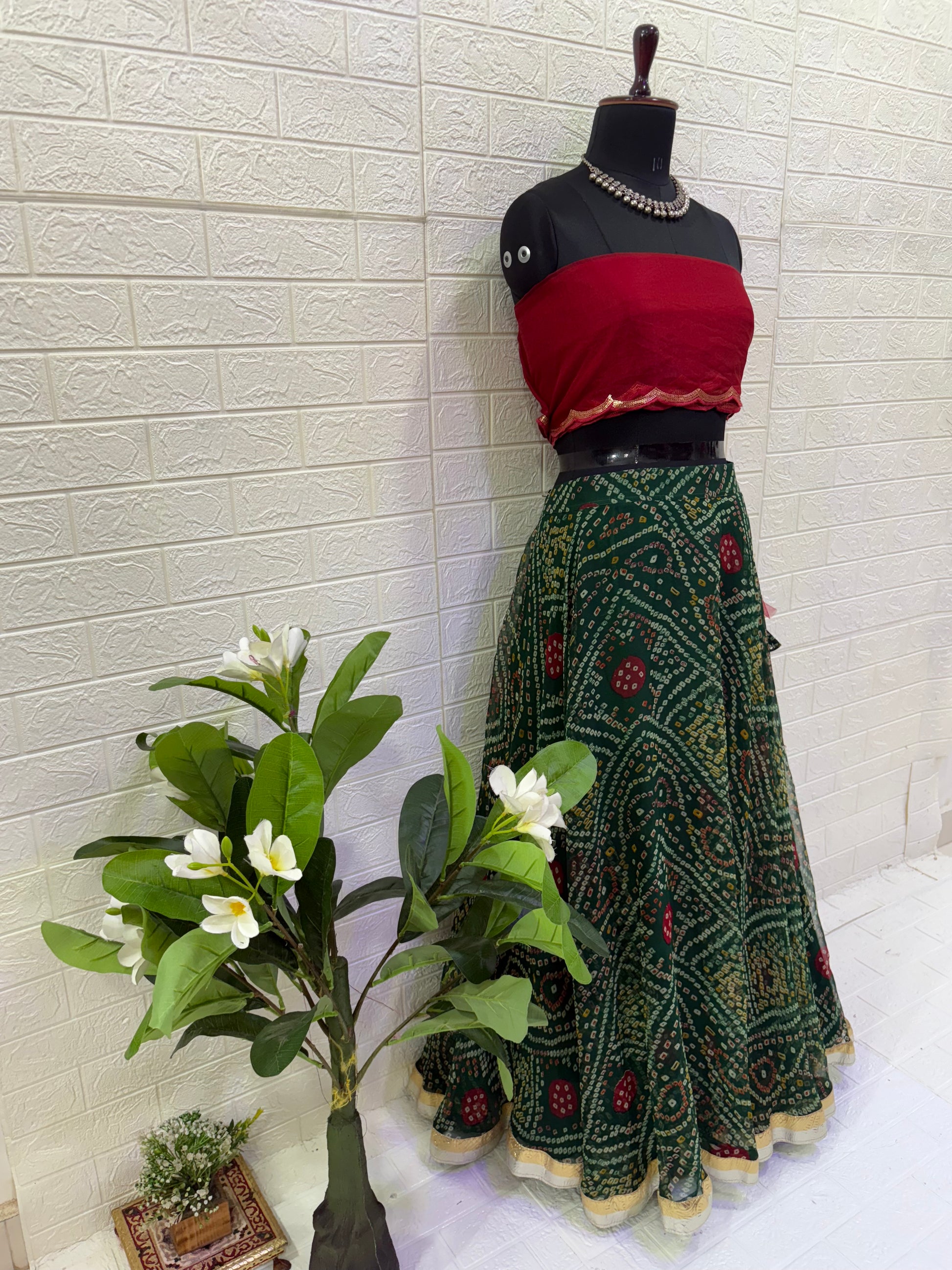 Name:
Emerald Bandhani Lehenga Set Crafted in pure Georgette bandhani print with a deep green flared lehenga and contrast red blouse, finished with golden lace border for a classic festive look.