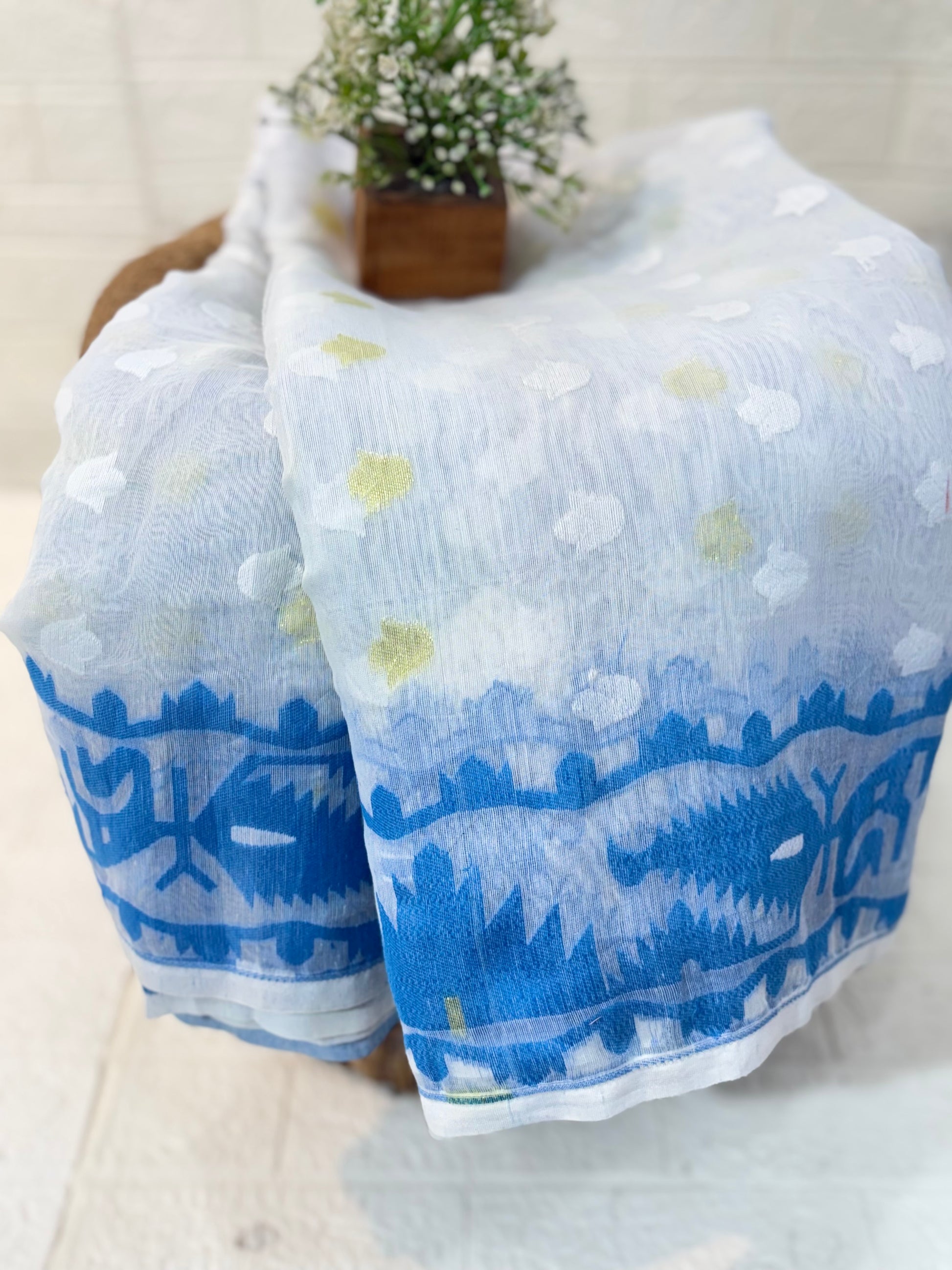 Neel Pushp Jamdani Saree
Crafted in soft cotton Jamdani, featuring a serene white body with delicate buti work and a rich blue woven border for an elegant, airy look.