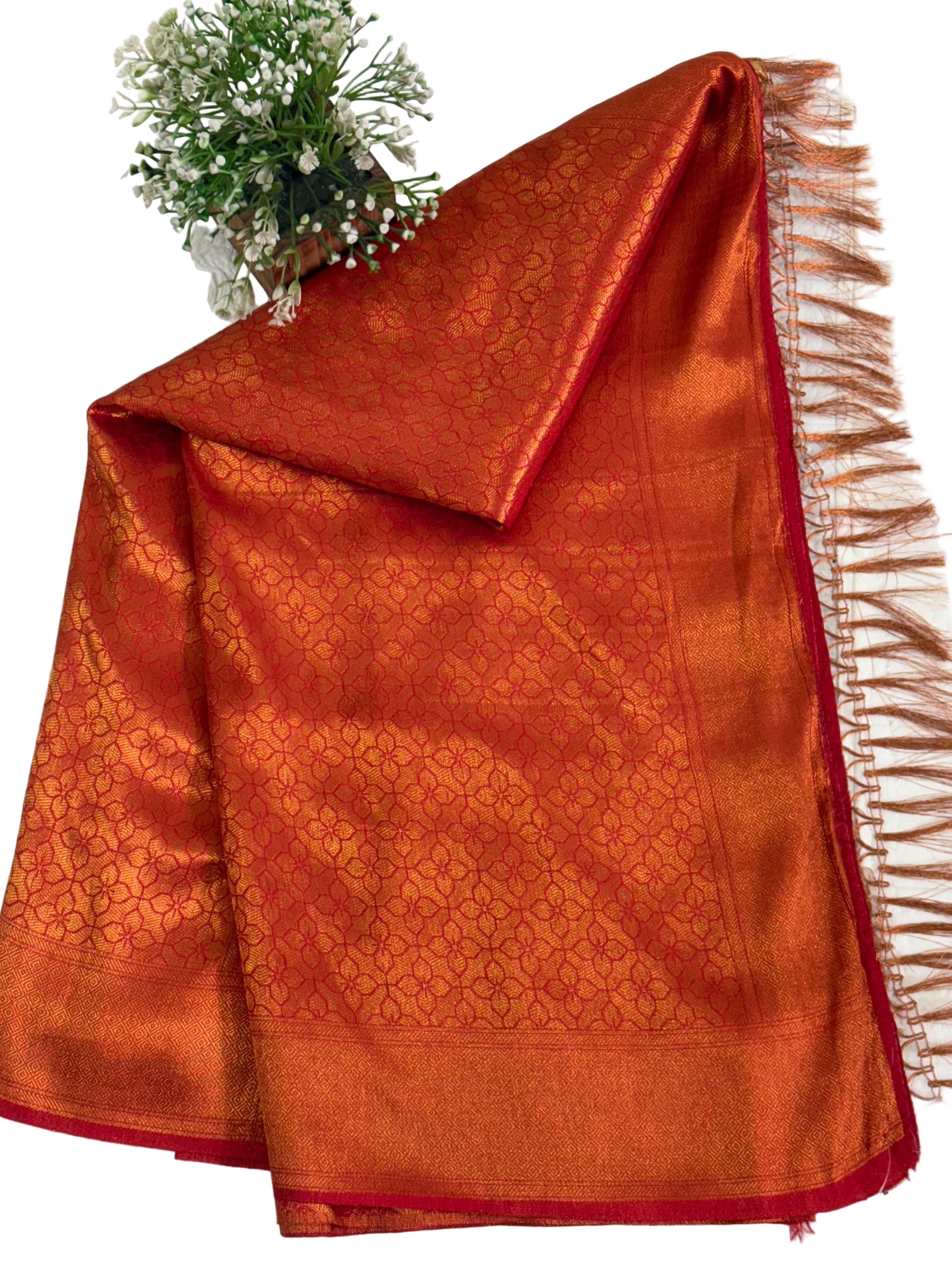 Dual-Tone Rust/Orange Saree kanchipuram silk Fabric A flowing fabric with a lustrous dual-tone (shot) effect, appearing to shift between rust/orange and gold, featuring subtle woven floral buttas/brocade work.