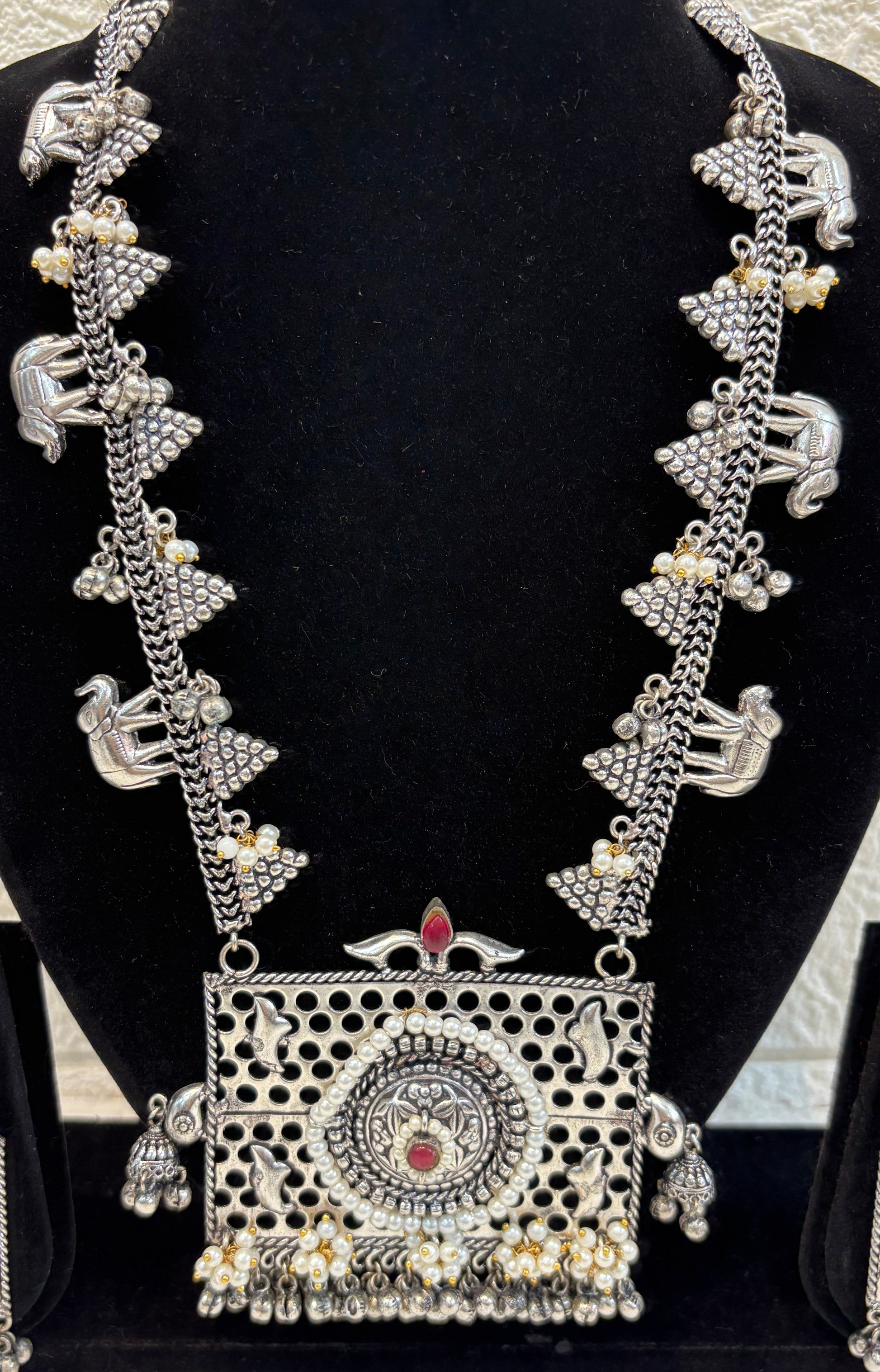 Name: Temple Design Oxidized Silver Necklace Set German silver with intricate elephant motifs, red stone highlights, and pearl bead detailing