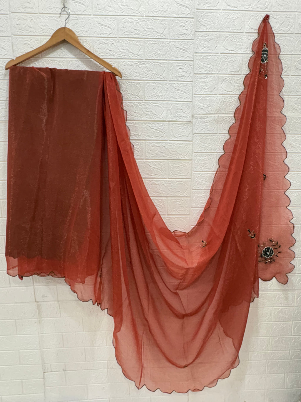 This fabric is a rust peach shimmer with embroiderd  organza with a soft shimmer, featuring delicate thread embroidery in Green and gold. The edges have a fine scallop finish, giving it a graceful drape.