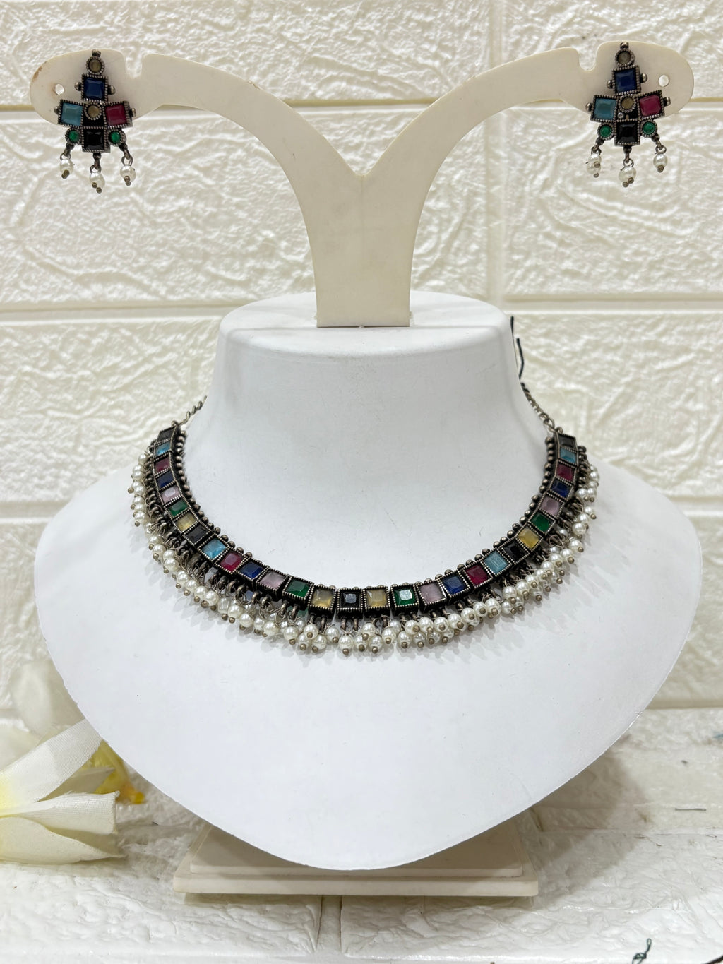 NAME: Boho Mirror Pearl Choker Set Oxidised silver choker adorned with multicolour square stones and pearl drops, paired with matching earrings. Ideal for festive and traditional looks.
