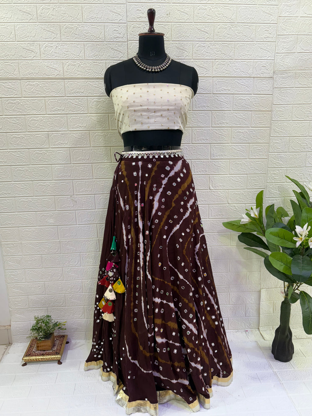 Name:
Mocha Swirl Bandhani Lehenga Crafted from rich brown soft cotton with traditional bandhani tie-dye patterns, paired with a off White soft blouse and statement tassels for a chic festive look.