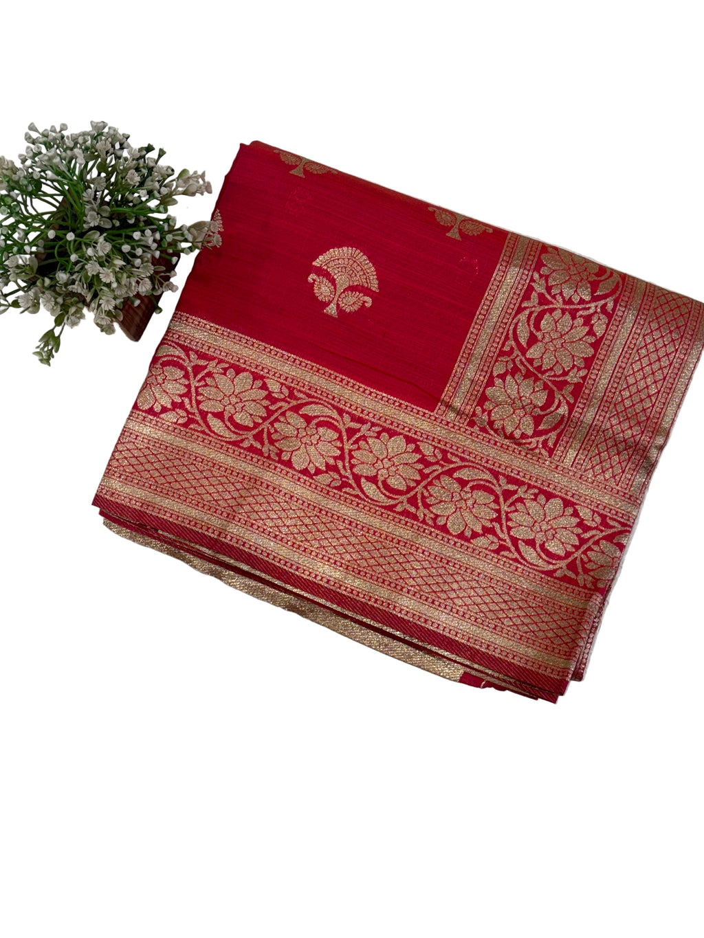 Name: Ruby Bloom Banarasi silk saree A rich ruby red Banarasi silk saree featuring intricate golden zari motifs with floral and lattice border detailing, adding a timeless traditional elegance to any ensemble.