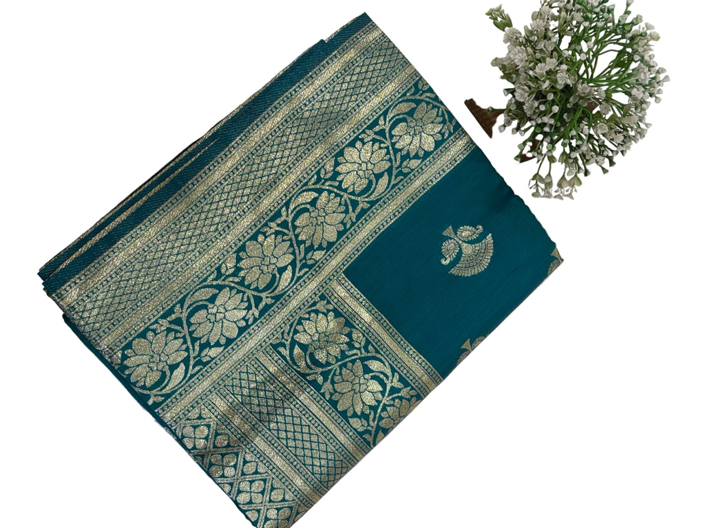 The saree appears to be a Banarasi Brocade Silk Saree.
It is made of silk with rich zari (metallic thread) brocade weaving, characteristic of the Banarasi style from Varanasi, India. The body features small fish (meen) motifs,