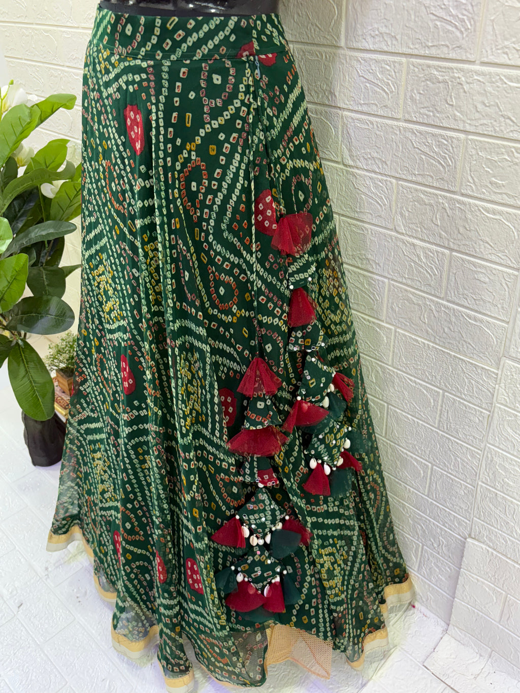 Name:
Emerald Bandhani Lehenga Set Crafted in pure Georgette bandhani print with a deep green flared lehenga and contrast red blouse, finished with golden lace border for a classic festive look.