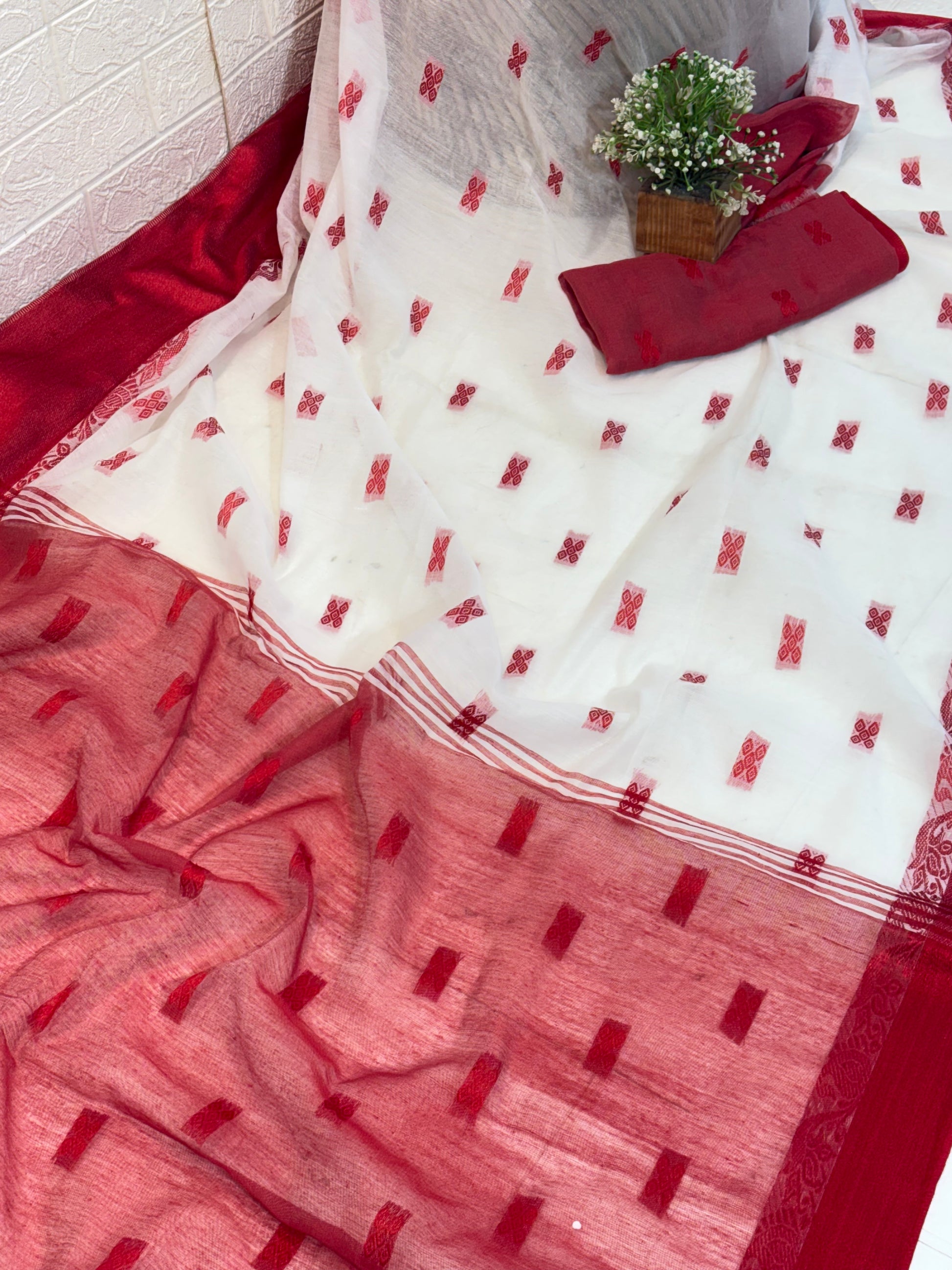 Cotton Jamdani Saree
Made from soft cotton Jamdani, featuring an elegant off-white body with red woven butis and a rich maroon-red border for a classic, graceful look.