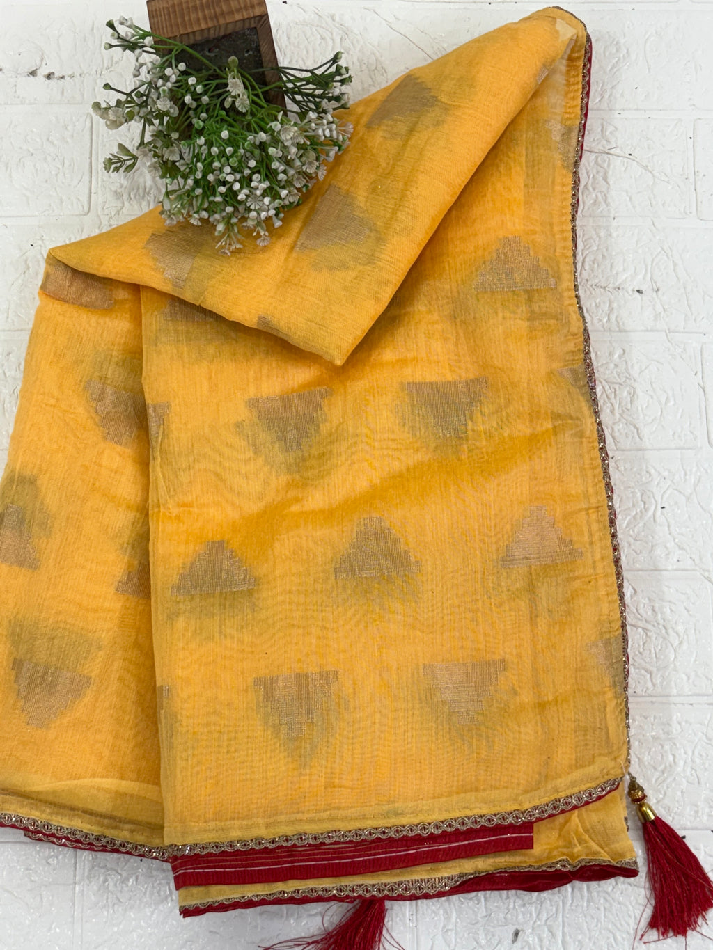The saree is most likely cotton silk a blend like  The lightweight, sheer nature of the yellow fabric, adorned with all-over gold zari woven triangular motifs, is characteristic of these silks. The geometric patte