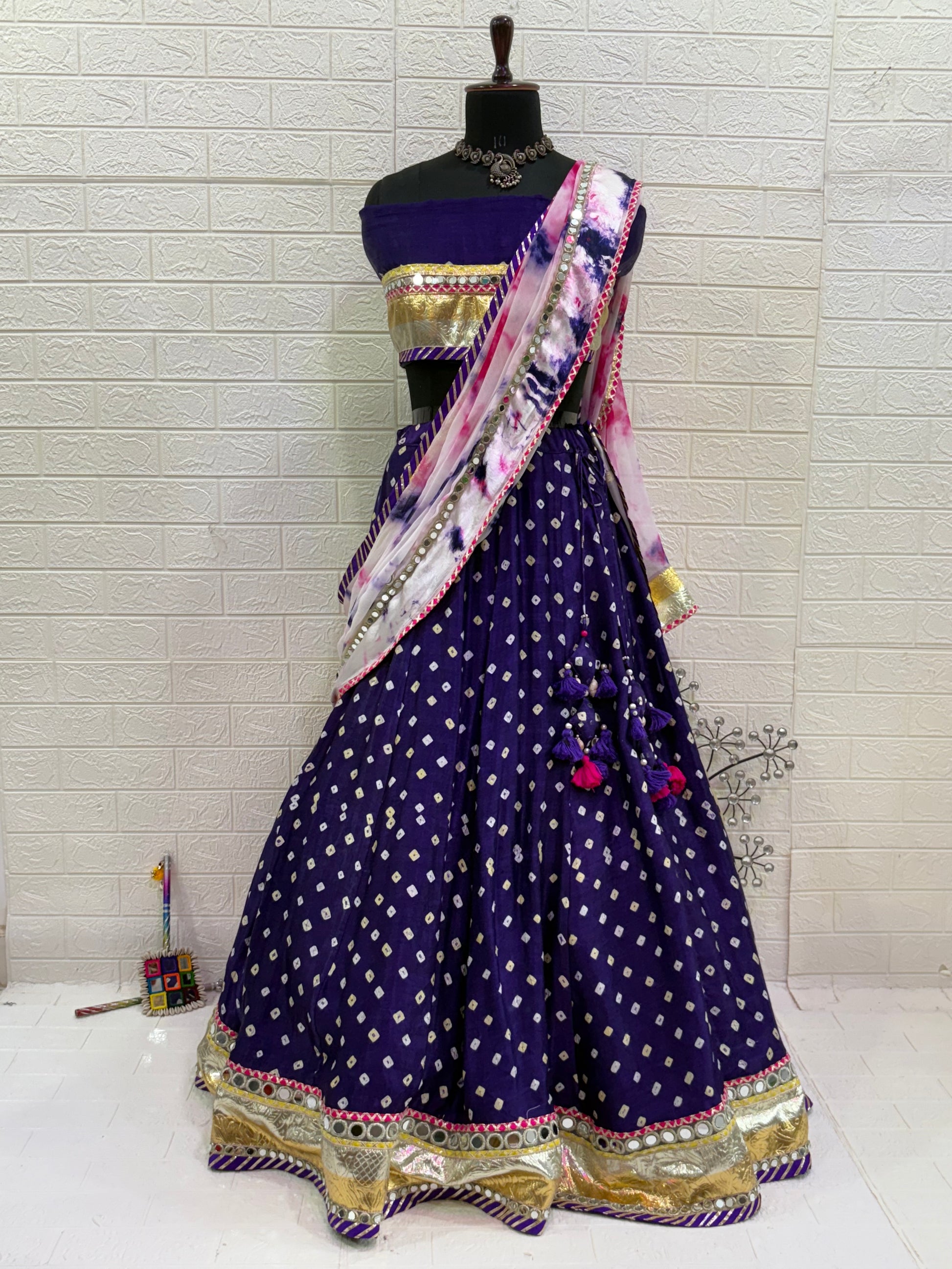 Name:
Royal Purple Bandhani Lehenga Set Made from soft synthetic satin Bandhni print with traditional paired with a contrast tie-dye dupatta and golden lace and long lumpy lace detailing for a vibrant festive look.