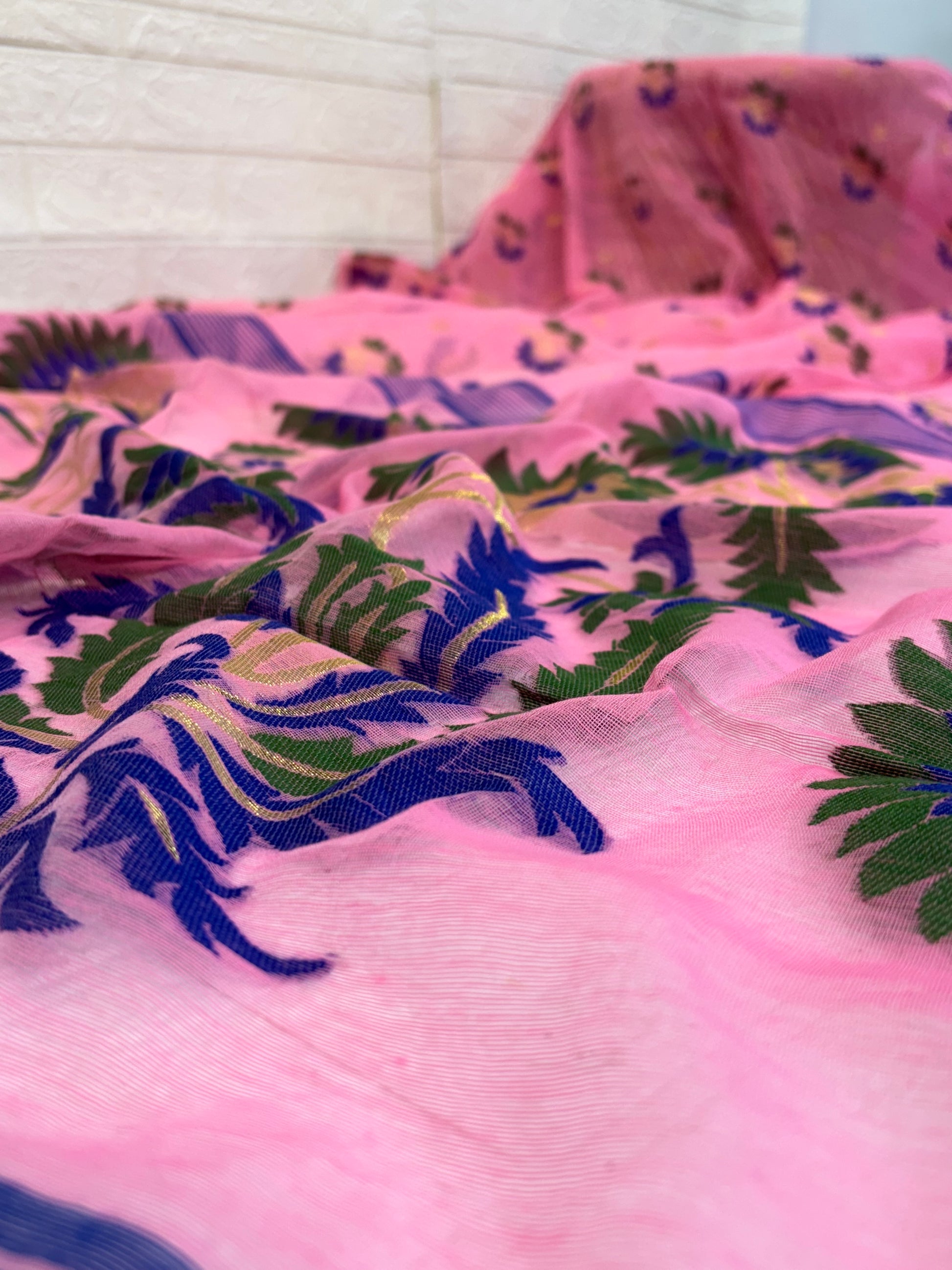 Jamdani Saree Crafted in soft, cotton Jamdani, featuring a delicate pink base with multicolour floral butis and a richly woven ornamental border for an elegant festive look.