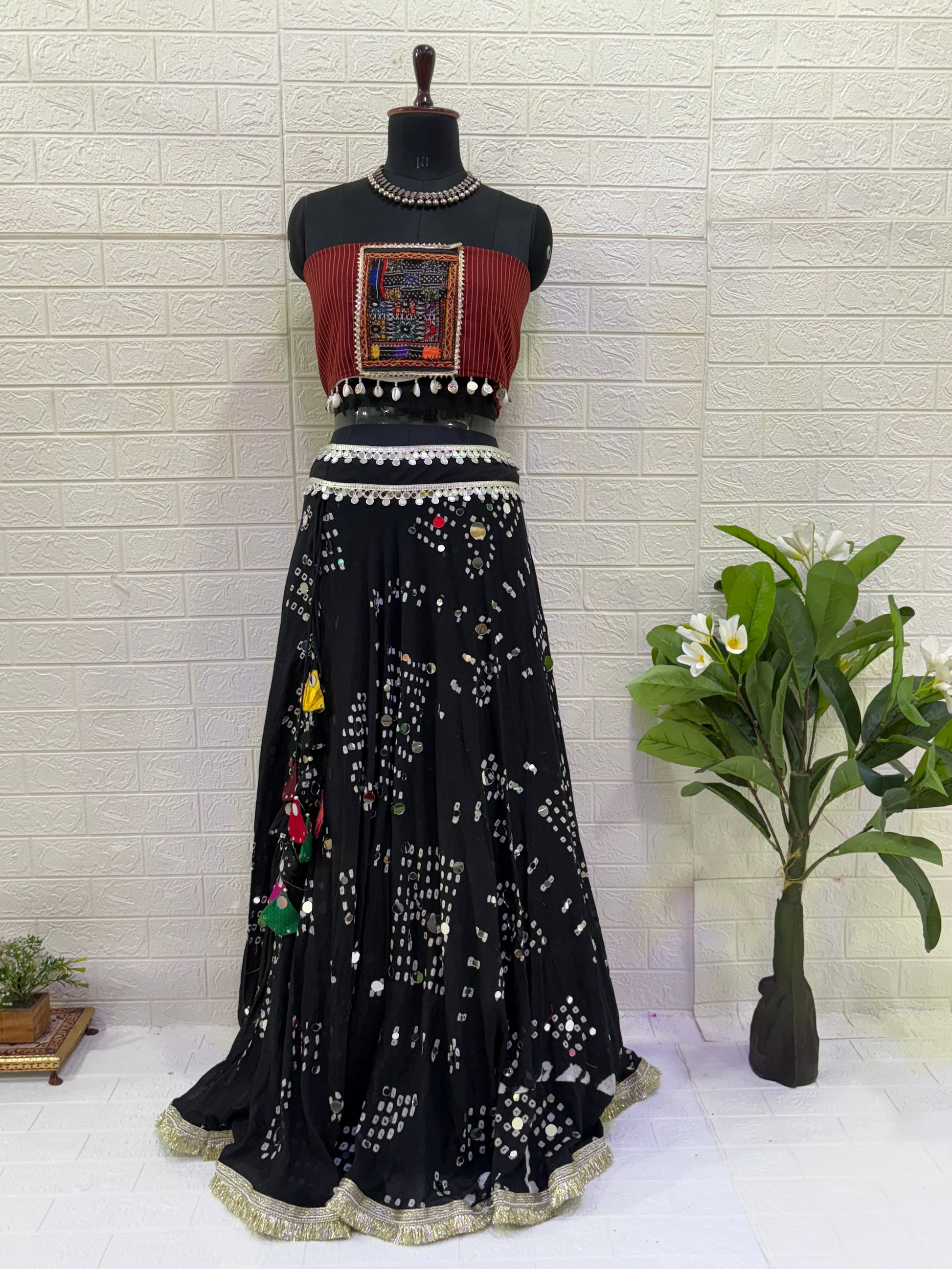 Name:
Midnight Mirror Bandhani Lehenga Elegant black cotton bandhani lehenga with mirror work and colorful tassels, paired with a tribal-inspired Ajrakh blouse for a bold festive vibe.