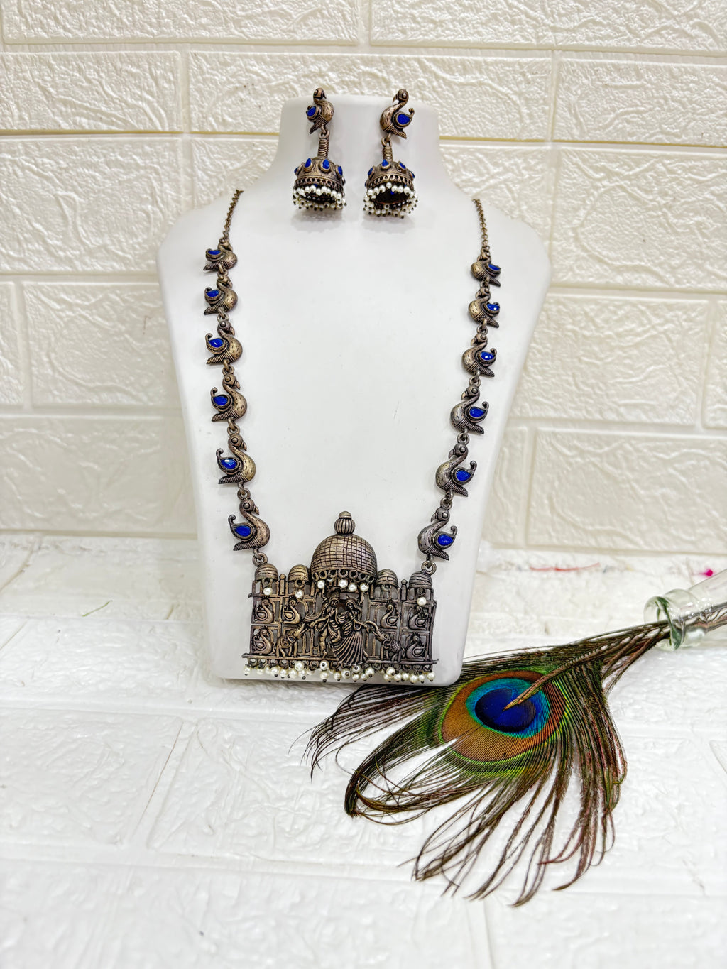 Name:
Heritage Dandiya Dome Necklace Set Oxidised silver necklace with temple-style dome pendant featuring dandiya dance motifs, accented with blue stone paisleys and matching jhumka earrings.
