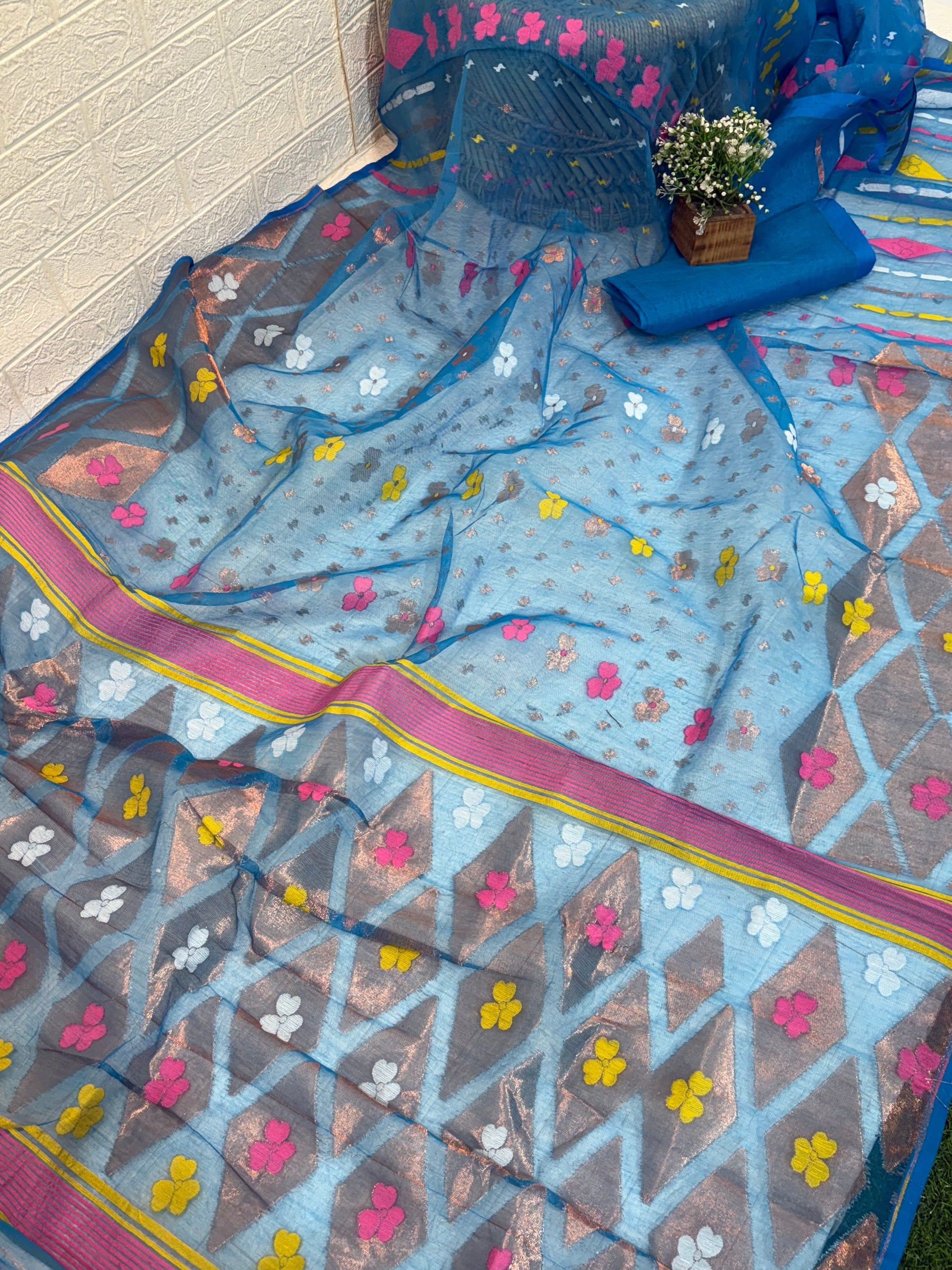 Jamdani Saree Made from airy cotton Jamdani, featuring a soothing blue base with multicolour floral butis and a beautifully woven contrast border for a fresh, elegant appeal.