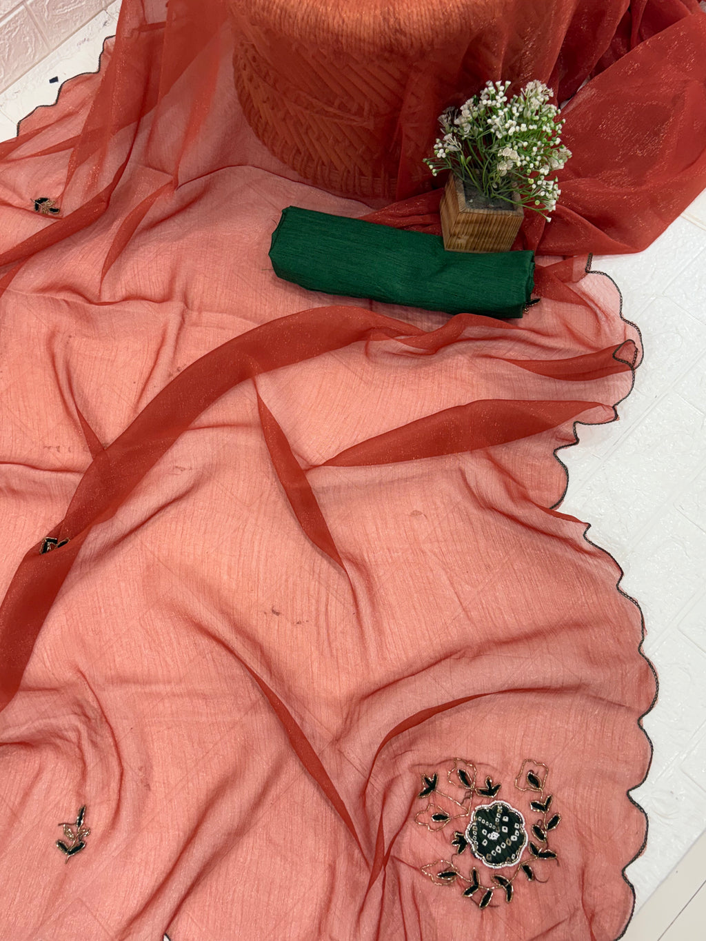 This fabric is a rust peach shimmer with embroiderd  organza with a soft shimmer, featuring delicate thread embroidery in Green and gold. The edges have a fine scallop finish, giving it a graceful drape.