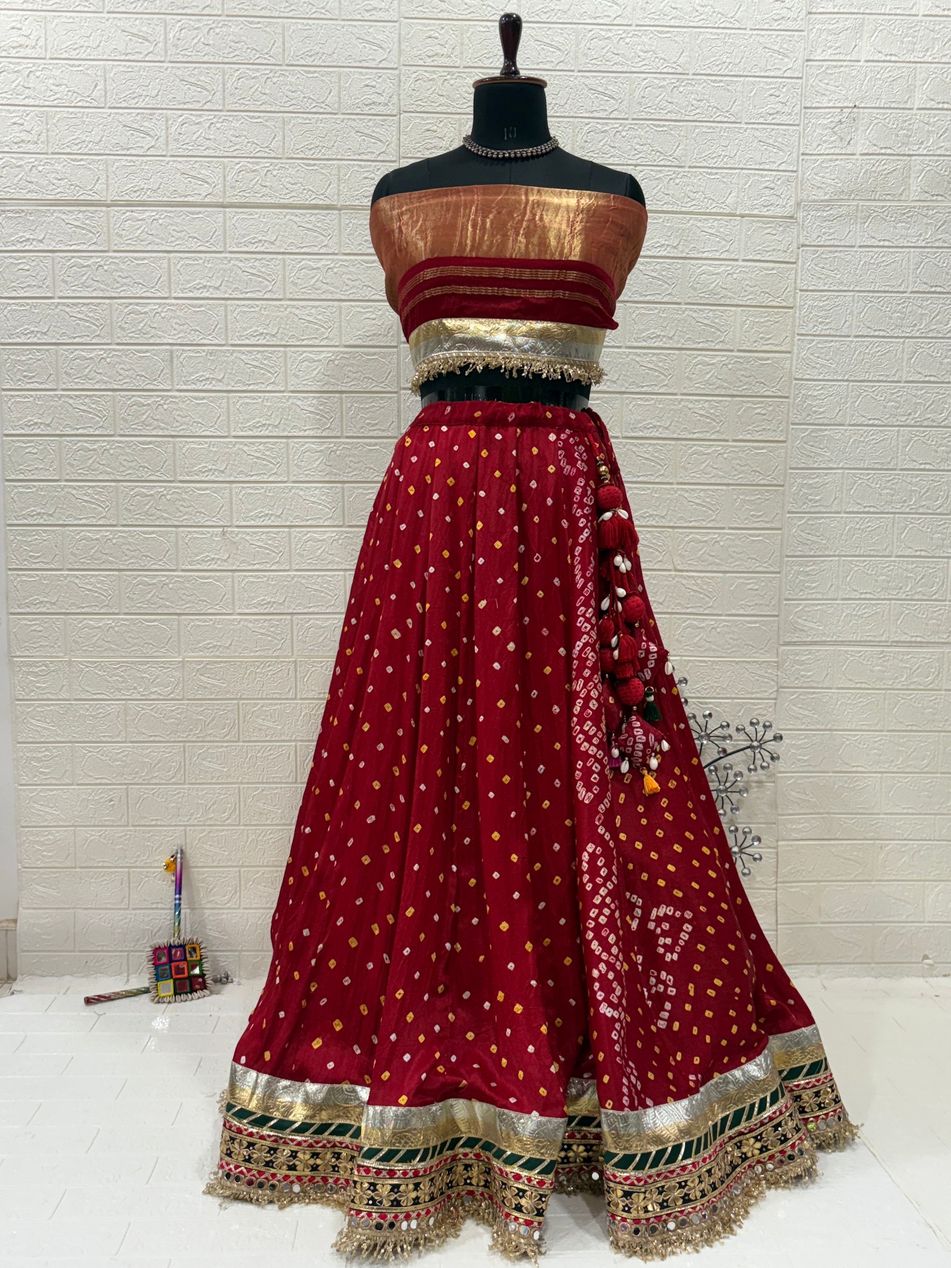 Name:
Red & Green Bandhni Lehenga Crafted in soft pure synthetic satin Bandhani print traditional paired with intricate gota-patti work, paired with a Bottle Green Organza dupatta embellished with mirror and zari lace for a festive, royal look.