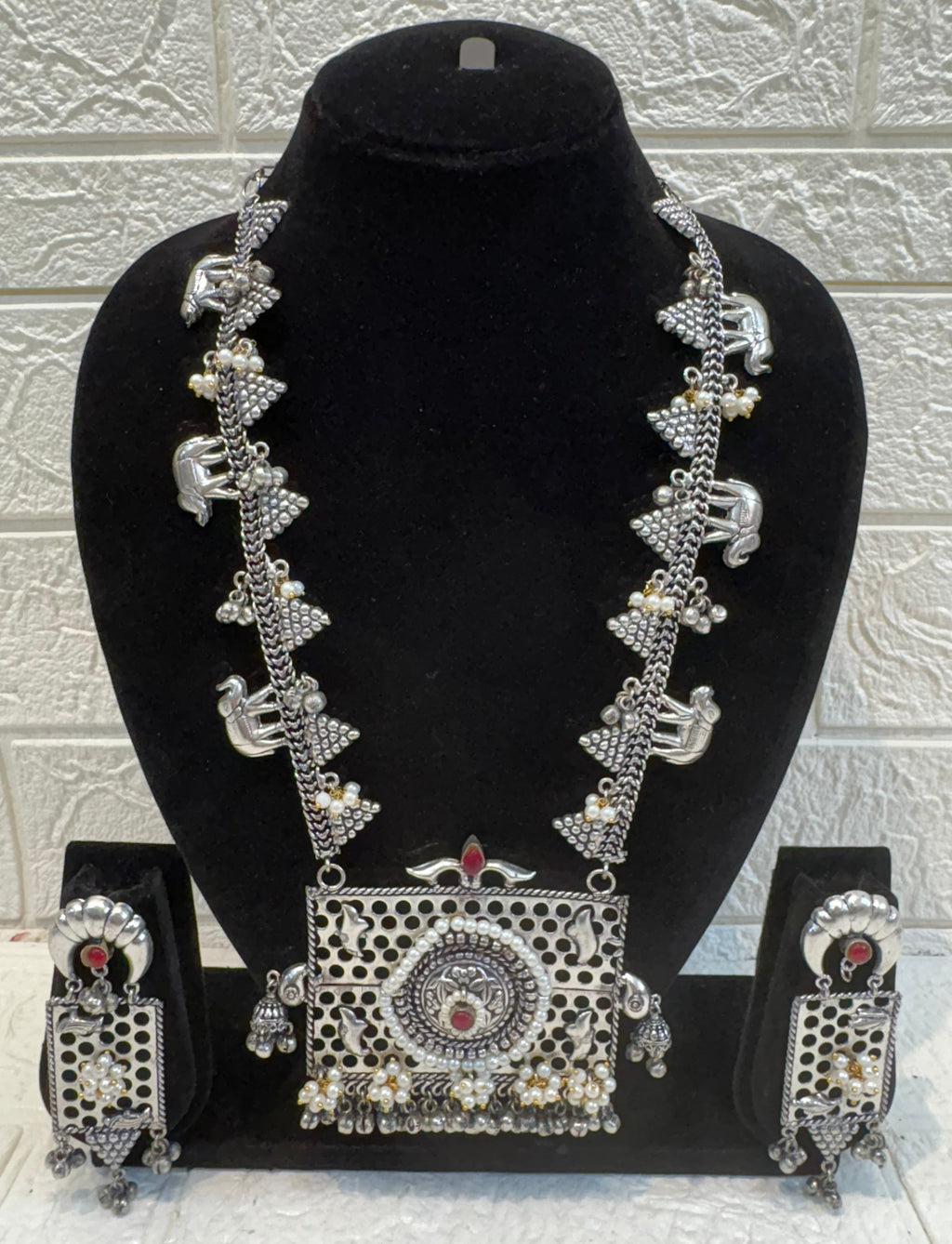 Name: Temple Design Oxidized Silver Necklace Set German silver with intricate elephant motifs, red stone highlights, and pearl bead detailing