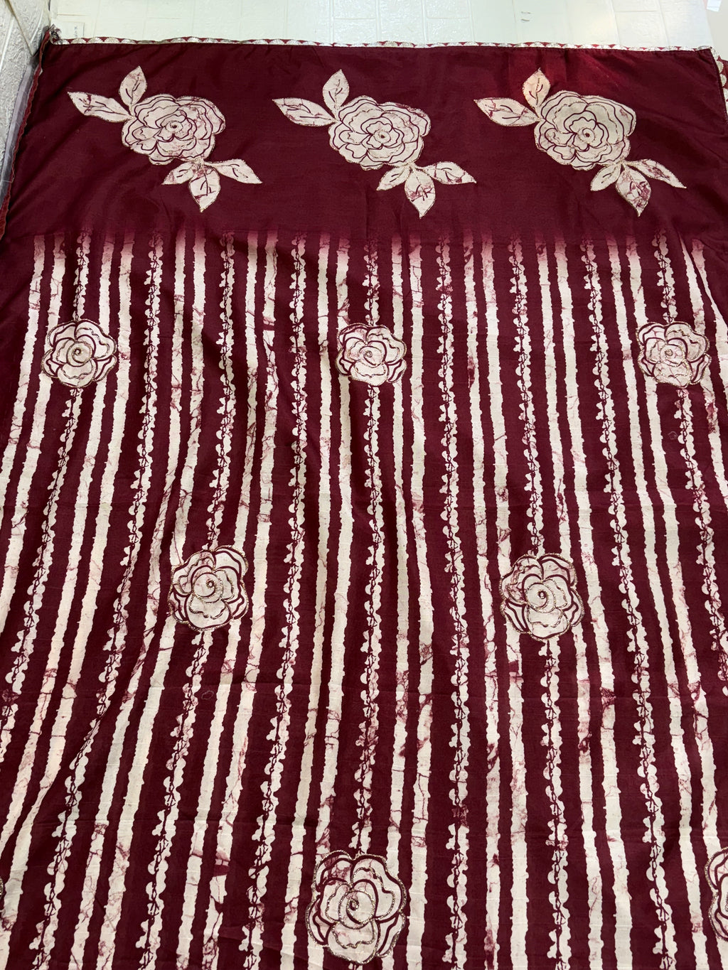 Name: Batik Print Saree/Fabric
Fabric: Typically Cotton or Cotton Silk Blend, sometimes Crepe or Silk, featuring a maroon and off-white wax-resist (Batik) print with rose and stripe motifs.