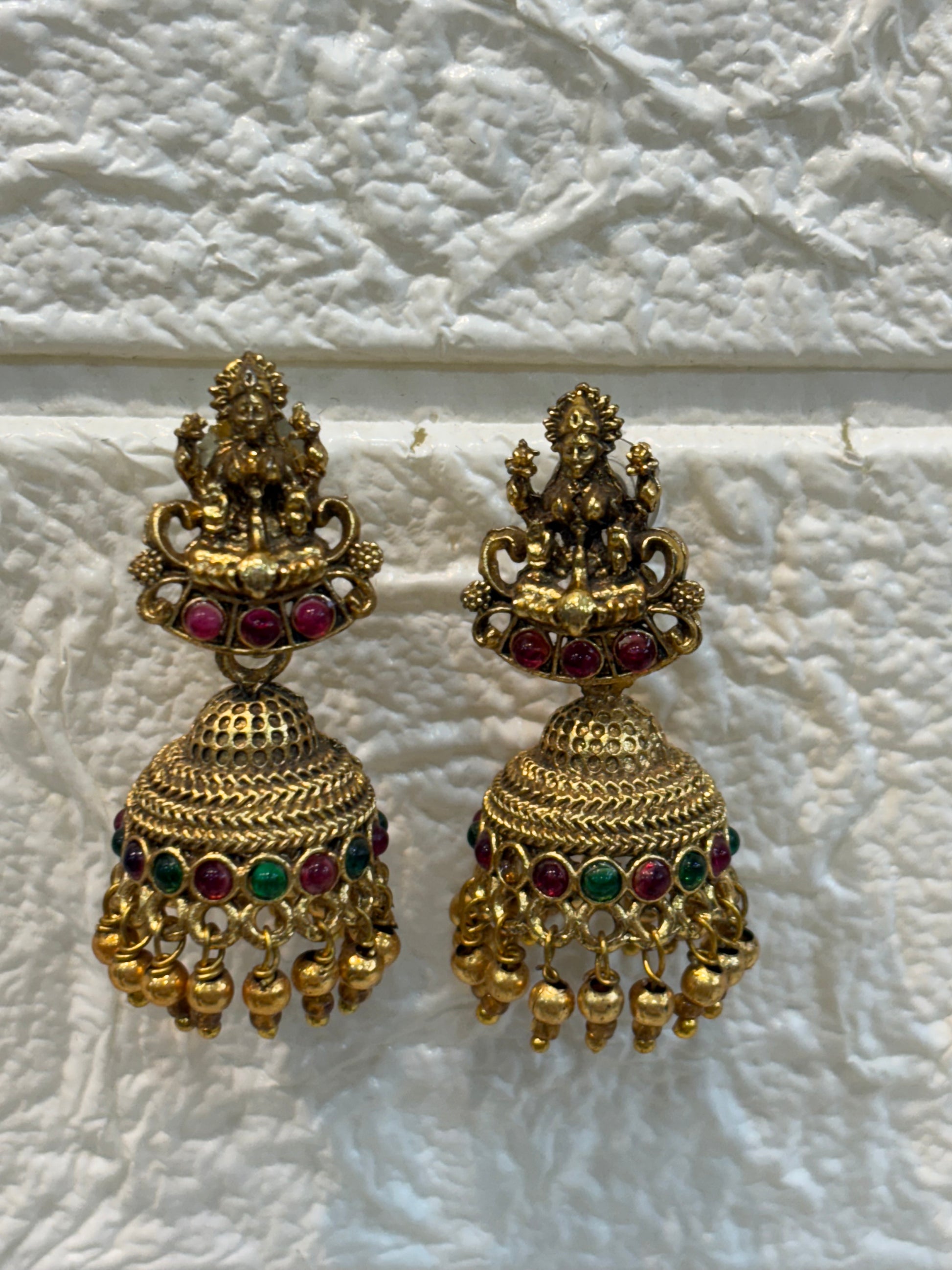 Antique gold-finish temple jewellery featuring intricate Goddess Lakshmi pendants, ruby-green stone detailing, and pearl drops—ideal for weddings and festive w