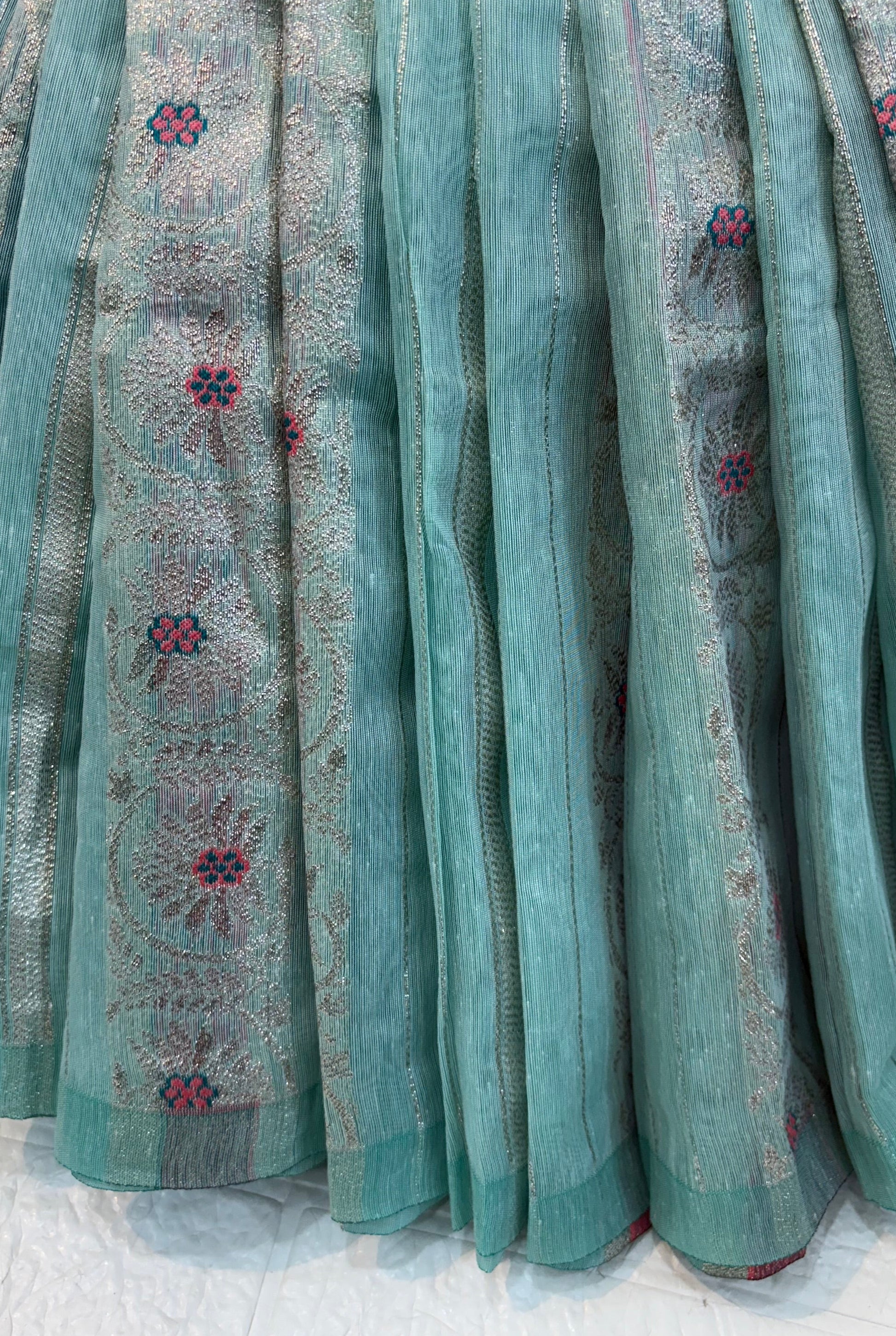 Zari Bloom Elegant sky blue soft cotton saree with soft zari stripes, delicate floral butti work, and a richly woven teal zari border for a refined festive look.