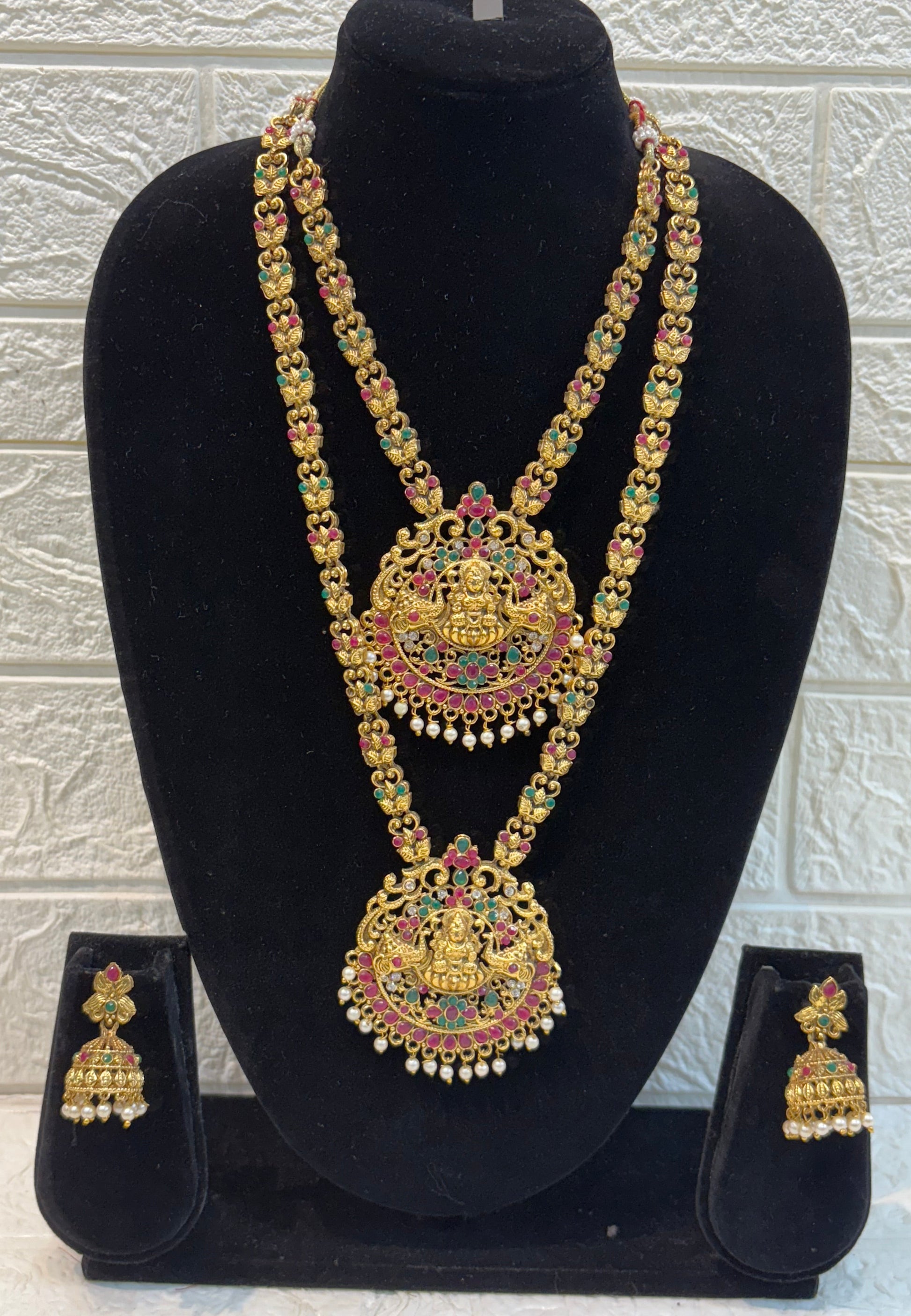 Antique gold-finish temple jewellery featuring intricate Goddess Lakshmi pendants, ruby-green stone detailing, and pearl drops—ideal for weddings and festive w