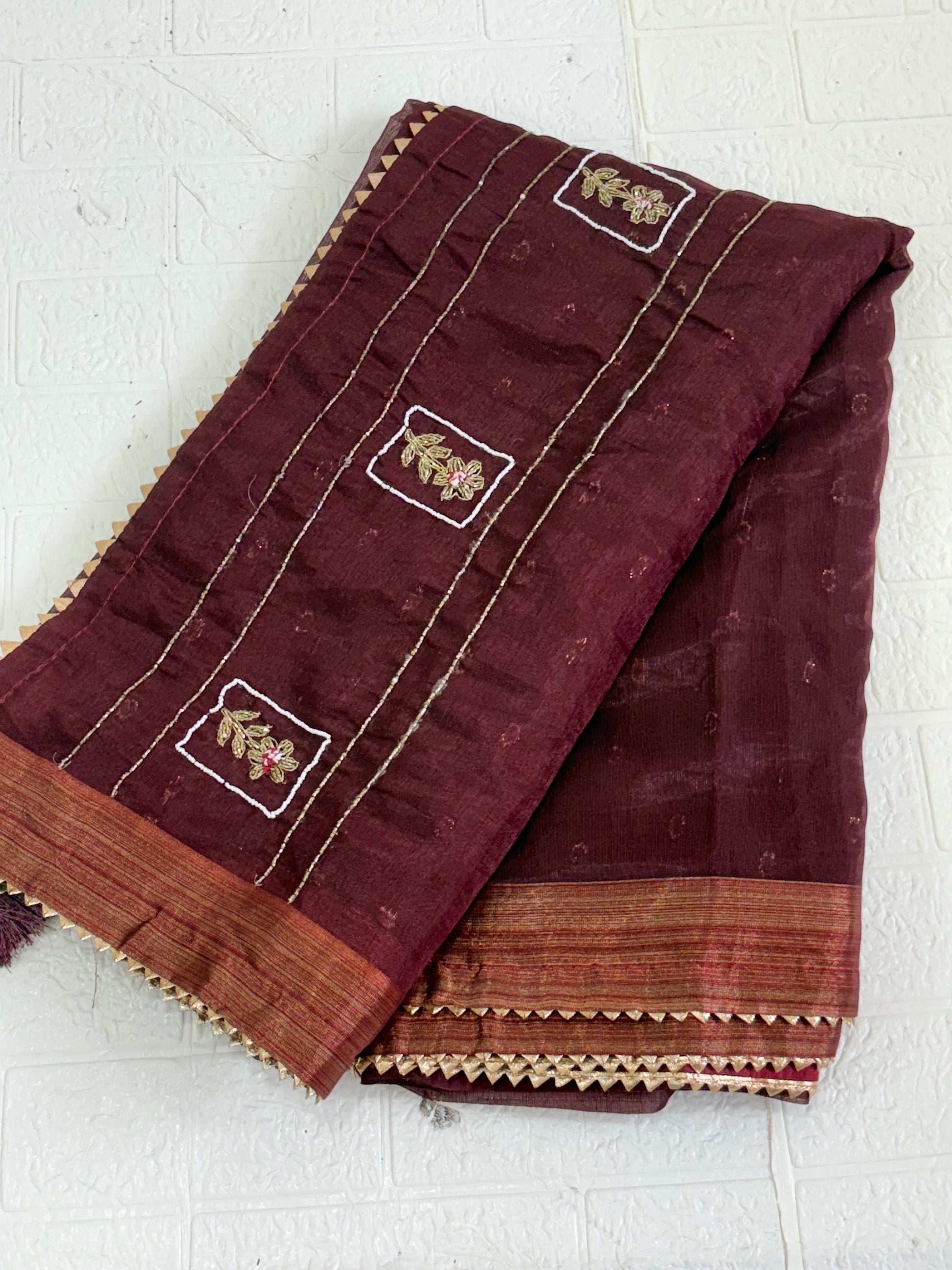 Name: Chanderi or Cotton Silk Saree Fabric The fine texture, sheen, and way the material is folded suggest a Chanderi or Cotton Silk Blend. The work is Zari Woven Stripes with Aari/Thread Embroidery motifs.