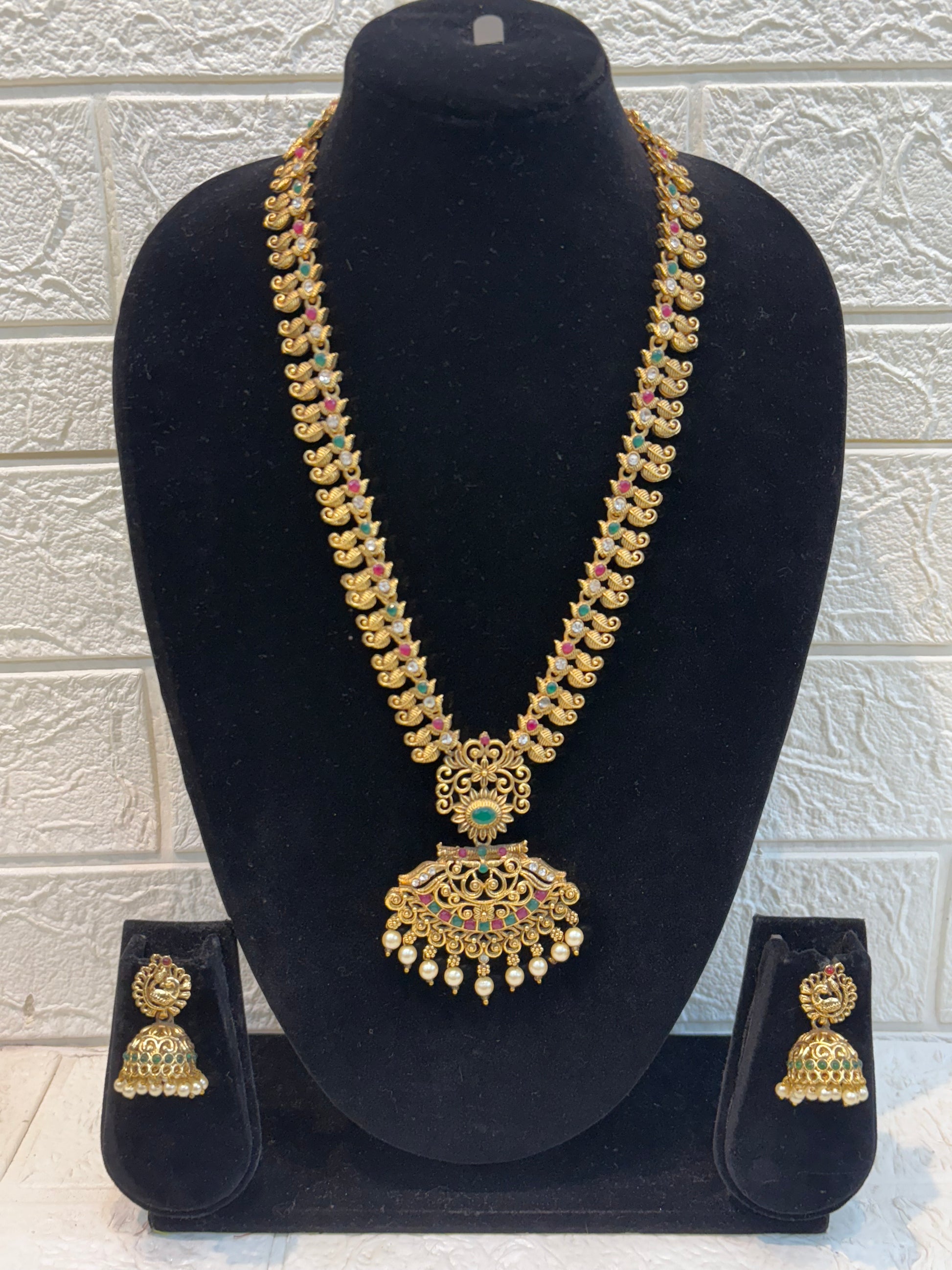 Traditional long haram featuring intricate motifs with ruby-green stone detailing and pearl drop pendant, paired with classic jhumka earrings—perfect for weddings and festive occasions.