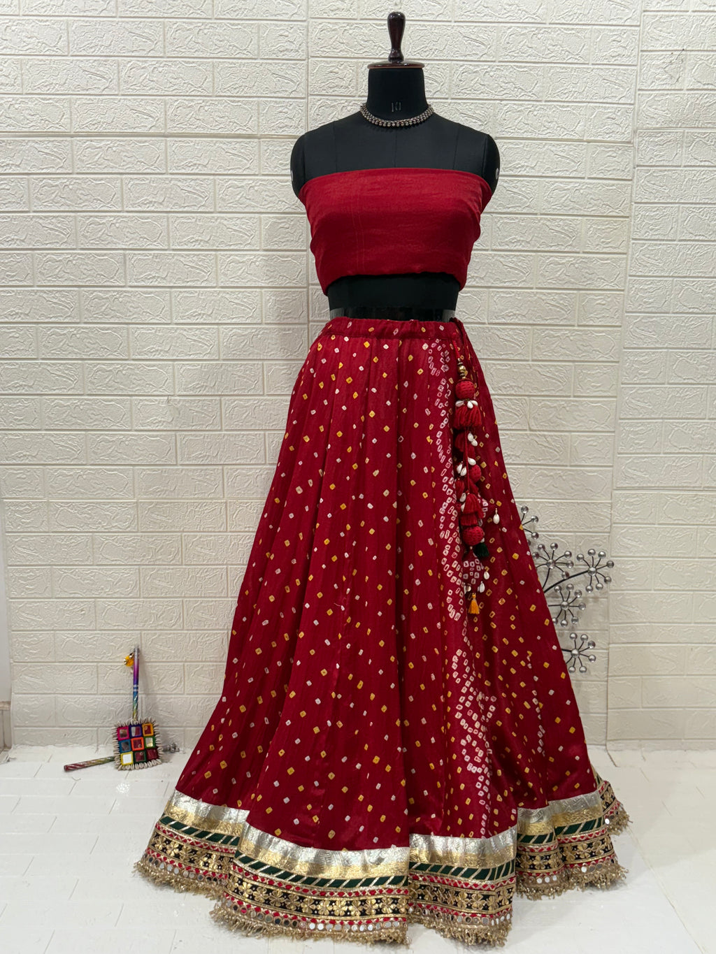 Name:
Red & Green Bandhni Lehenga Crafted in soft pure synthetic satin Bandhani print traditional paired with intricate gota-patti work, paired with a Bottle Green Organza dupatta embellished with mirror and zari lace for a festive, royal look.