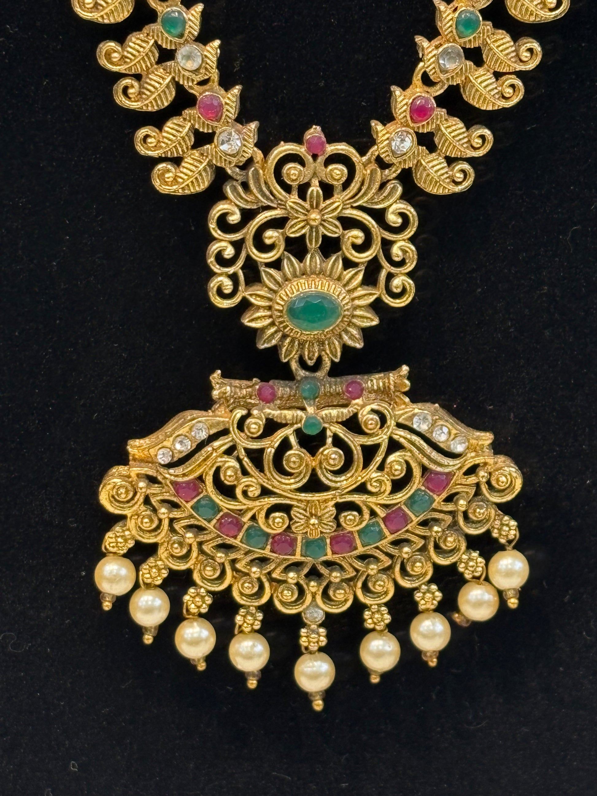 Traditional long haram featuring intricate motifs with ruby-green stone detailing and pearl drop pendant, paired with classic jhumka earrings—perfect for weddings and festive occasions.