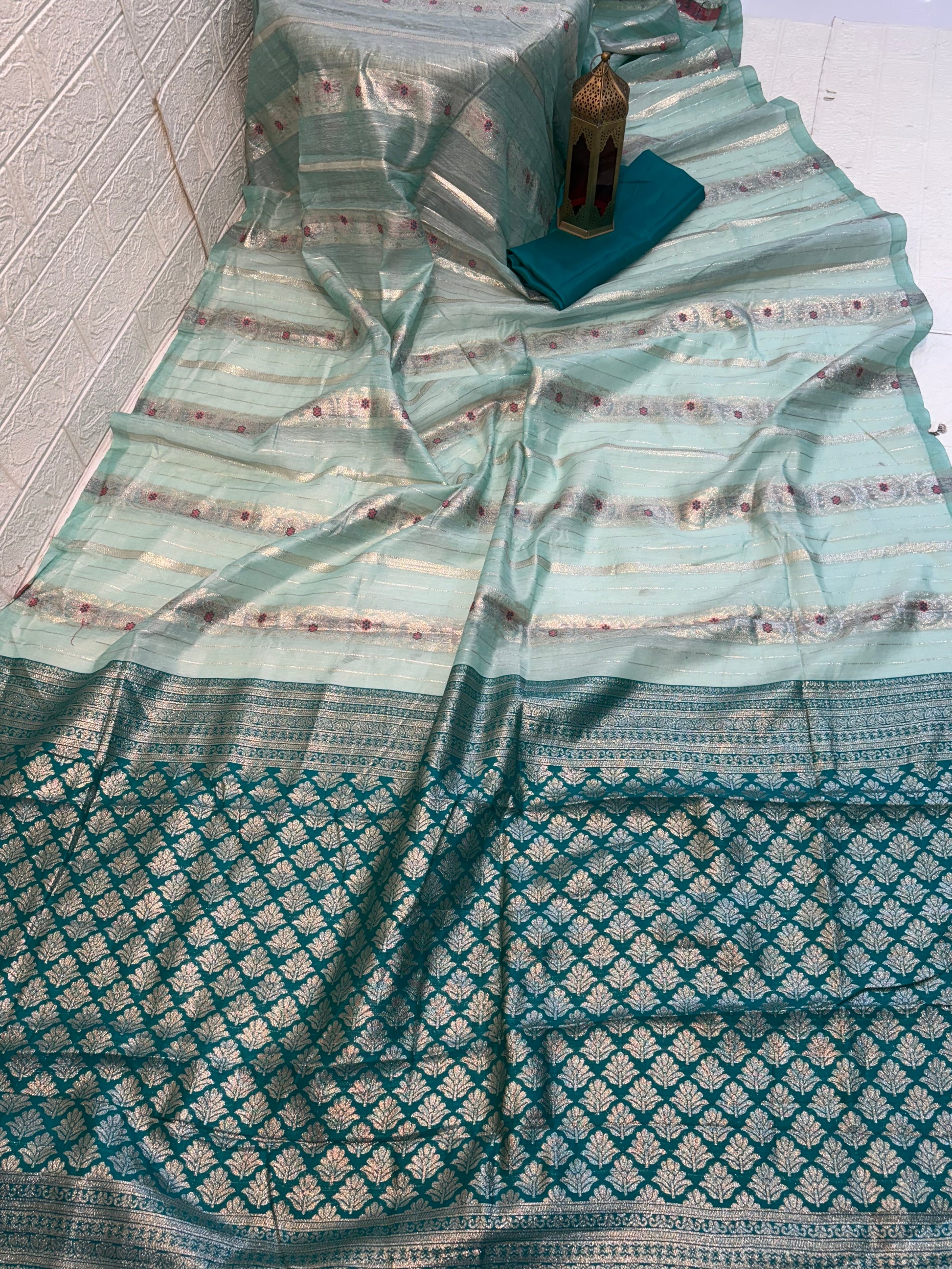 Zari Bloom Elegant sky blue soft cotton saree with soft zari stripes, delicate floral butti work, and a richly woven teal zari border for a refined festive look.