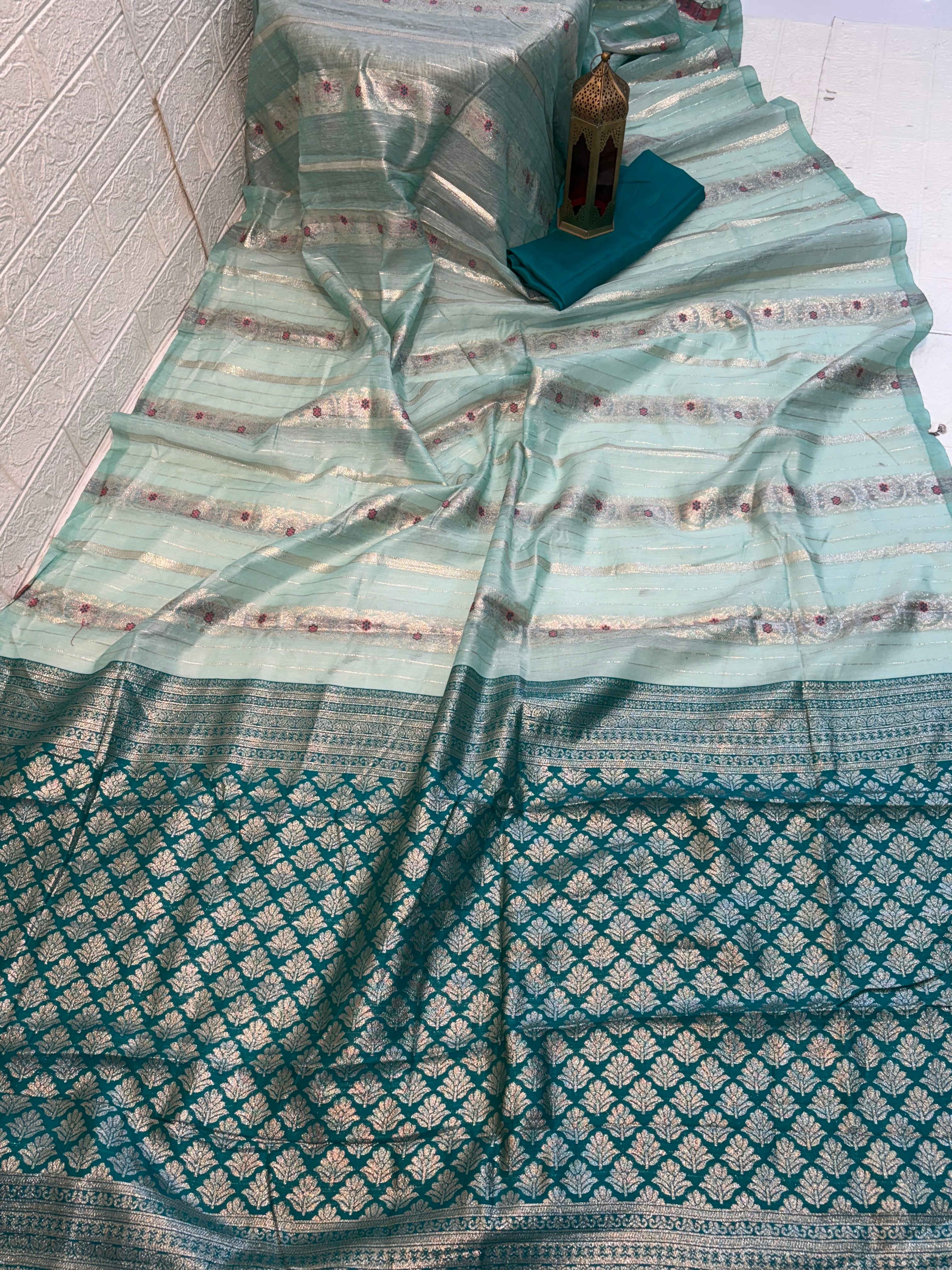 Zari Bloom Elegant sky blue soft cotton saree with soft zari stripes, delicate floral butti work, and a richly woven teal zari border for a refined festive look.