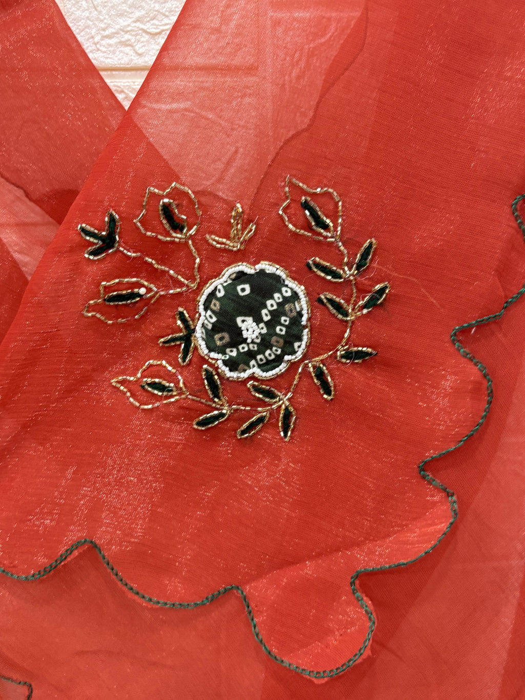 This fabric is a rust peach shimmer with embroiderd  organza with a soft shimmer, featuring delicate thread embroidery in Green and gold. The edges have a fine scallop finish, giving it a graceful drape.