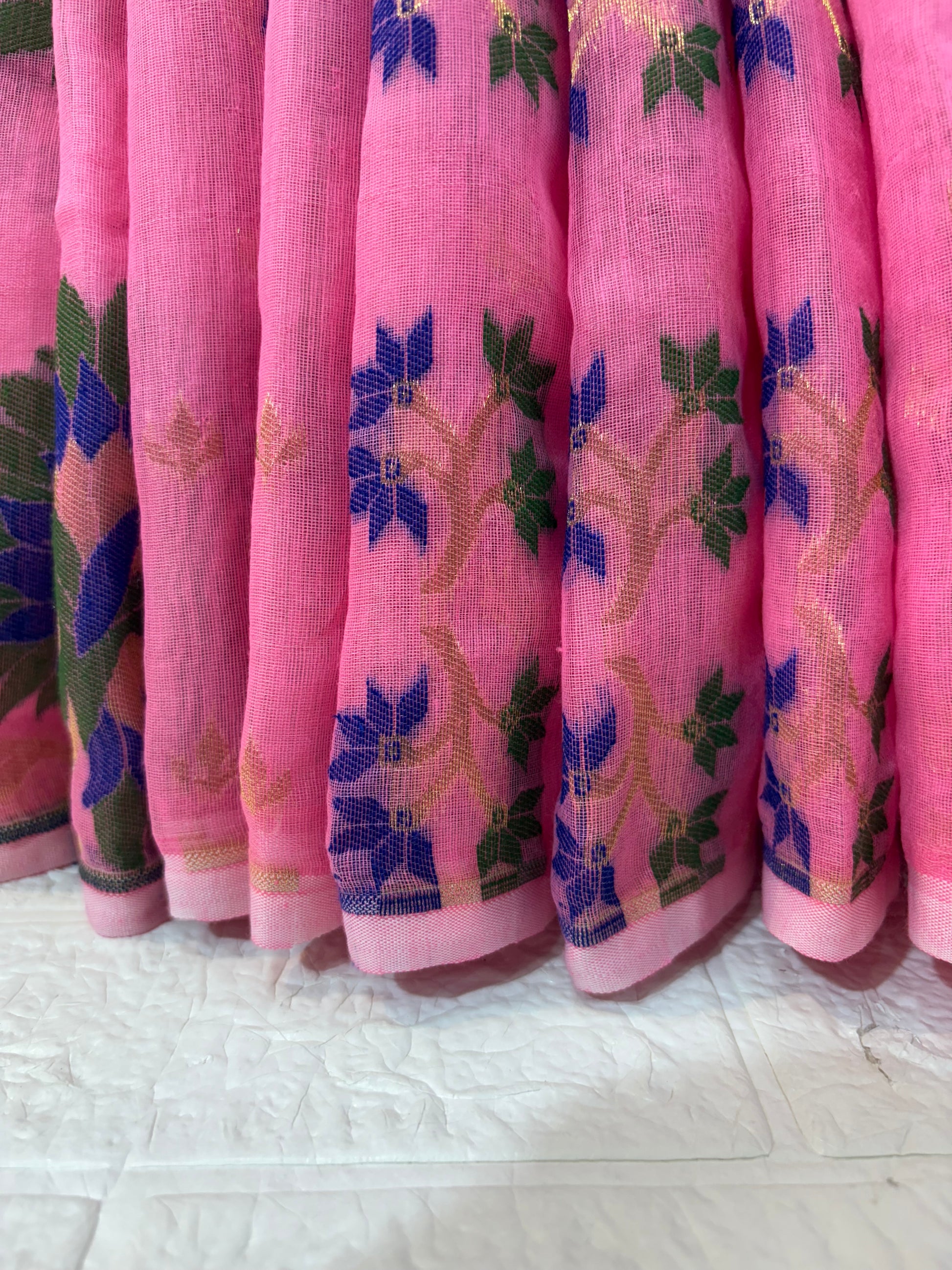 Jamdani Saree Crafted in soft, cotton Jamdani, featuring a delicate pink base with multicolour floral butis and a richly woven ornamental border for an elegant festive look.