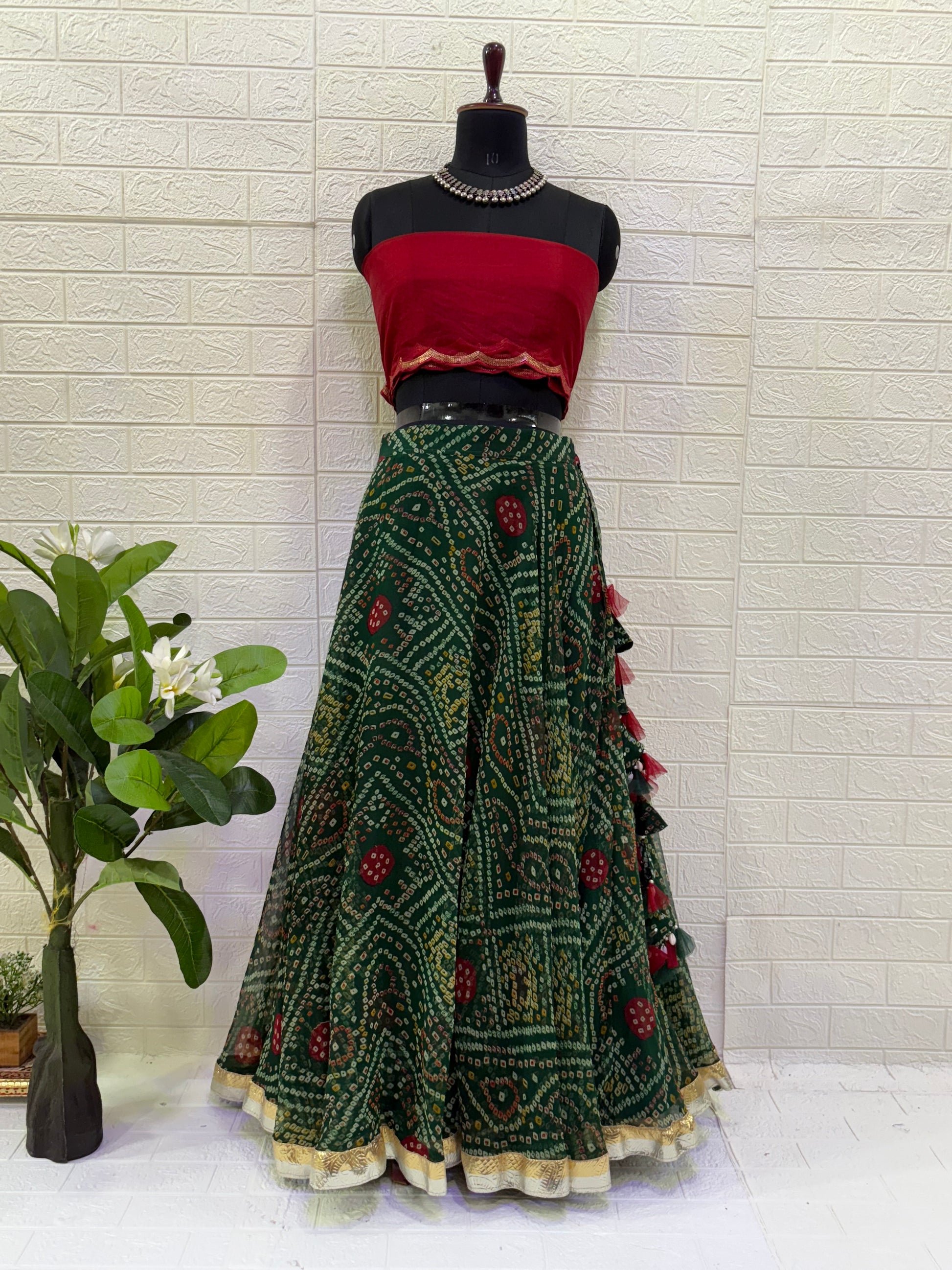 Name:
Emerald Bandhani Lehenga Set Crafted in pure Georgette bandhani print with a deep green flared lehenga and contrast red blouse, finished with golden lace border for a classic festive look.