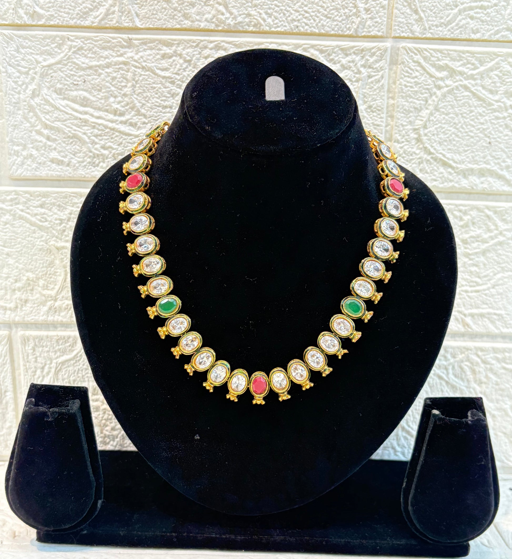 Elegant antique-finish necklace featuring oval-cut white stones highlighted with ruby and emerald accents, offering a classic and graceful look for festive and wedding wear.