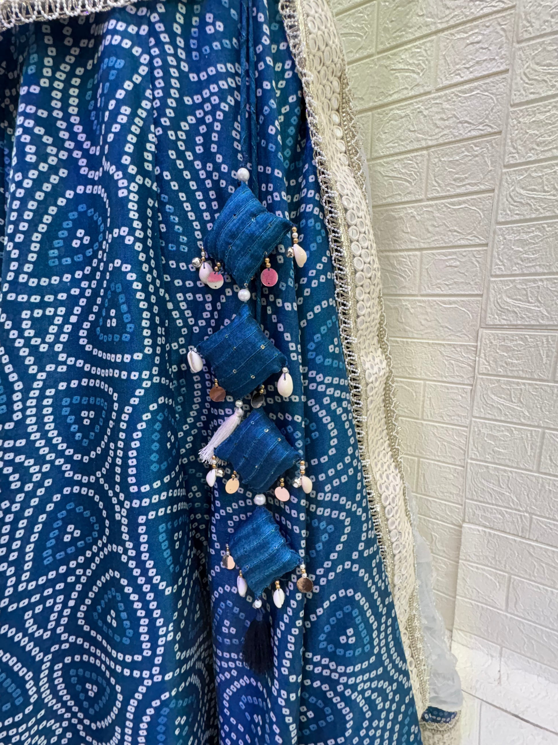 Name:  Blue Bandhani  Lehenga Set Made from soft cotton  Bandhani  print fabric with a mirror work border and paired with a chiffon white dupatta – perfect for festive and traditional celebrations.