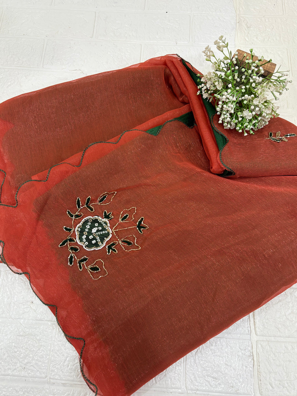 This fabric is a rust peach shimmer with embroiderd  organza with a soft shimmer, featuring delicate thread embroidery in Green and gold. The edges have a fine scallop finish, giving it a graceful drape.