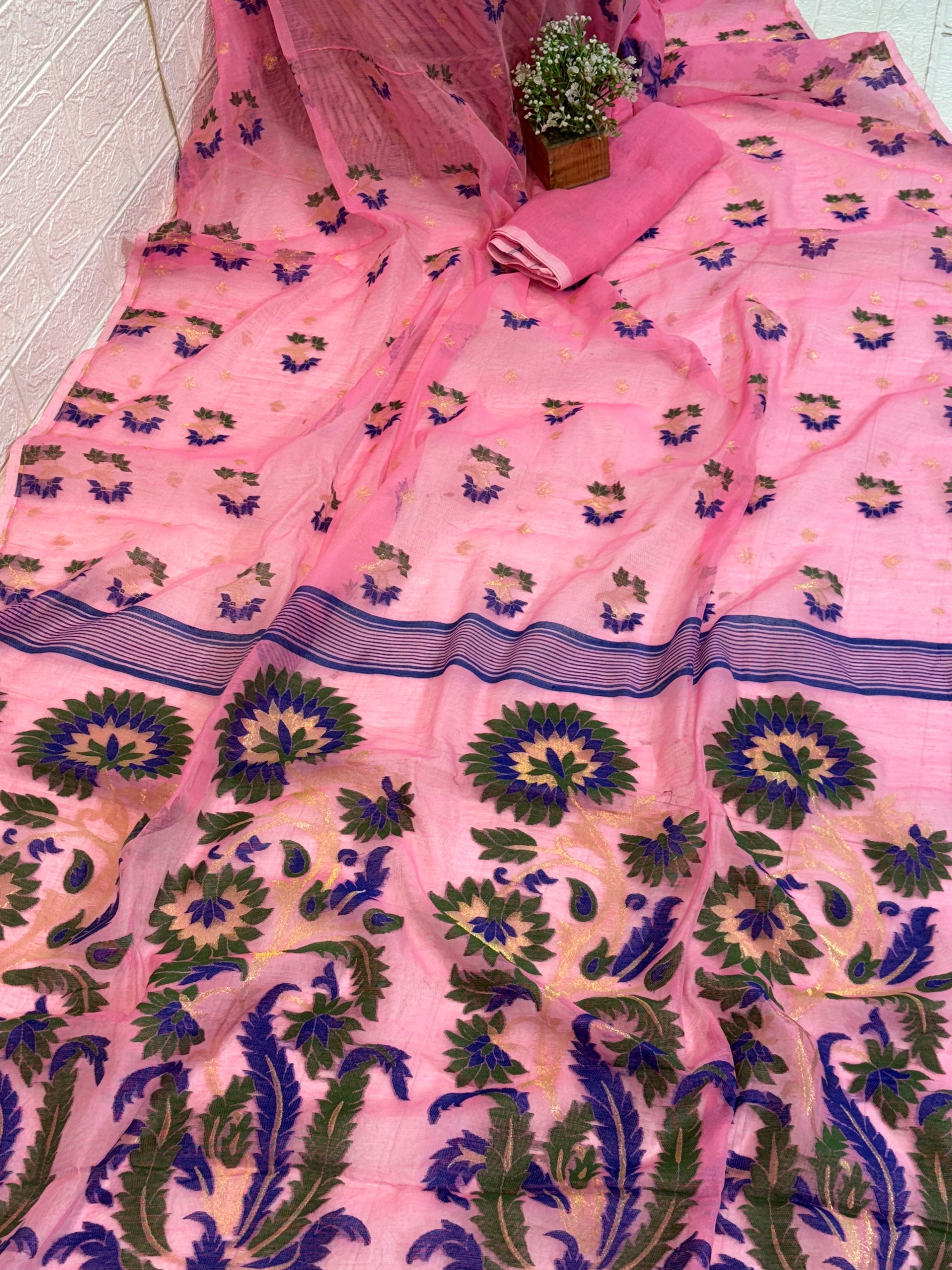 Jamdani Saree Crafted in soft, cotton Jamdani, featuring a delicate pink base with multicolour floral butis and a richly woven ornamental border for an elegant festive look.