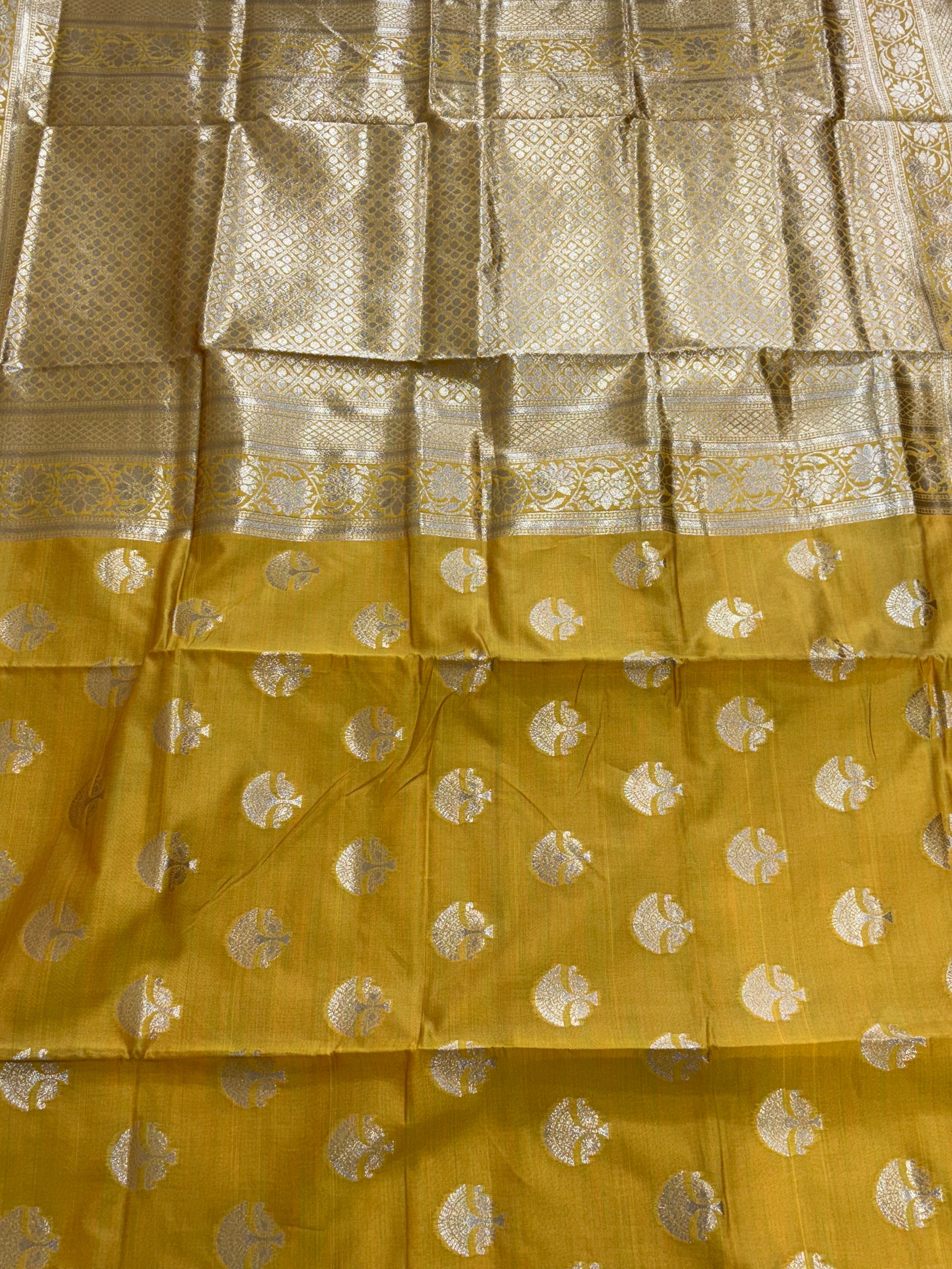 The saree appears to be a Banarasi brocade silk saree it is made of silk with rich zari (metallic thread) brocade weaving characteristic of the Banarasi style from Varanasi India the body features small fish (meen) motifs