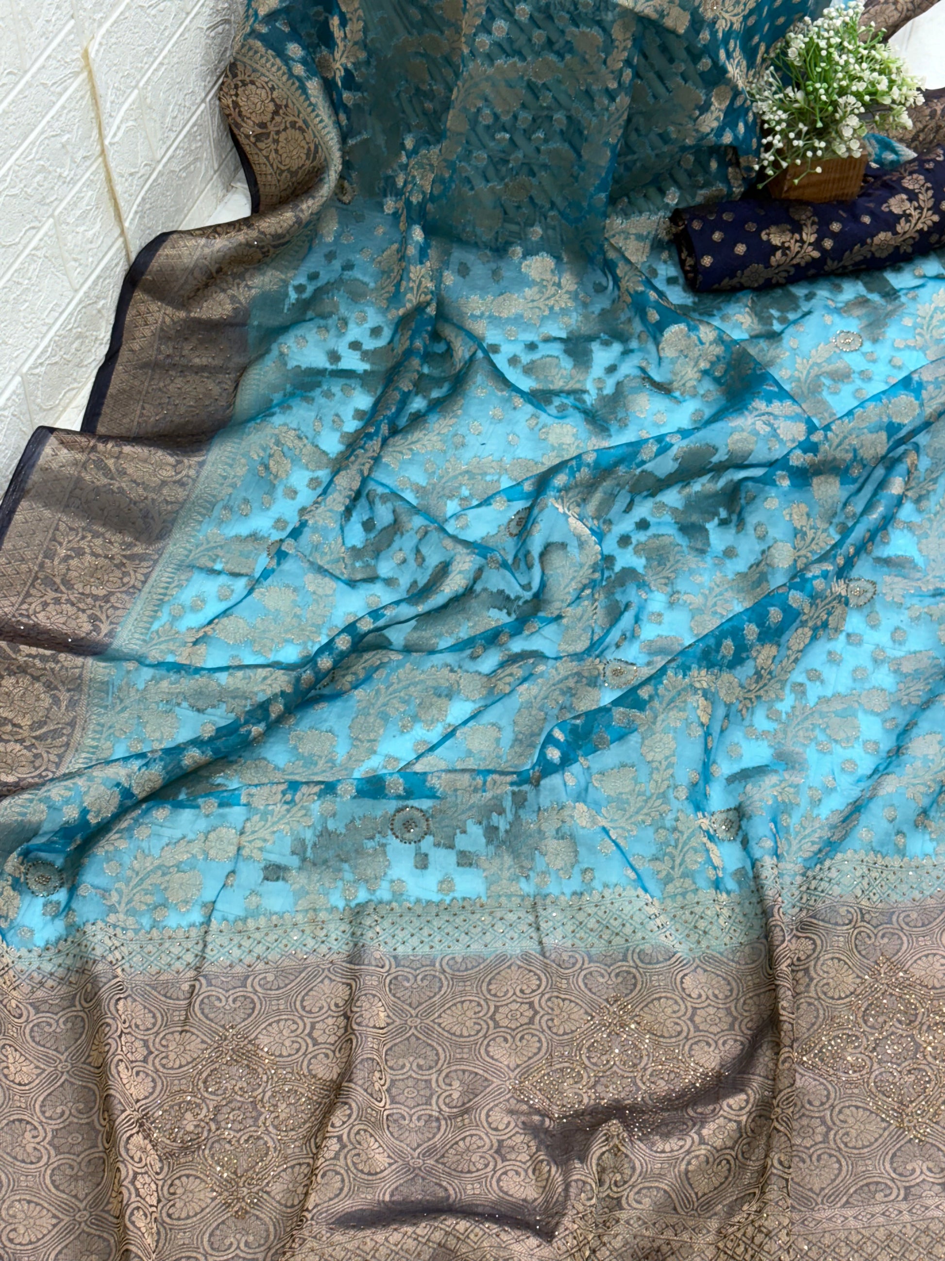 Fabric This is a Banarasi organza Saree with colour is blue heavy gold Zari Brocade (or Katan Silk) weave and subtle sequin/stone embellishments.