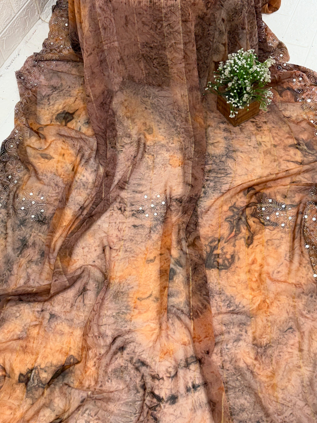 Saree with Woven mirror or peach and light black colour small motif The pattern is a  (motif) woven the sheer georgette fabric Silk.  with mirror work in saree This fabric is known for its sheer, lightweight texture