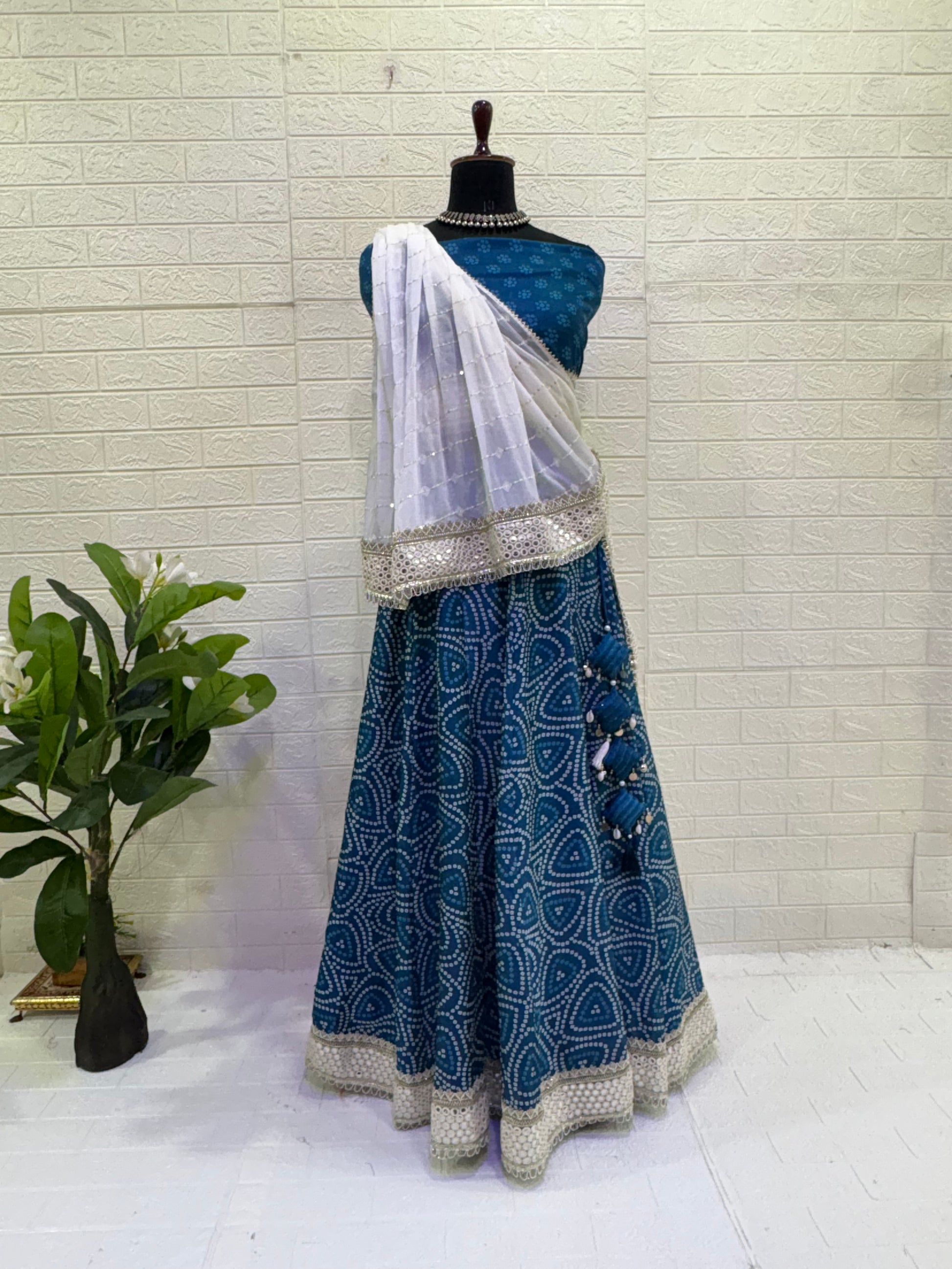 Name:  Blue Bandhani  Lehenga Set Made from soft cotton  Bandhani  print fabric with a mirror work border and paired with a chiffon white dupatta – perfect for festive and traditional celebrations.