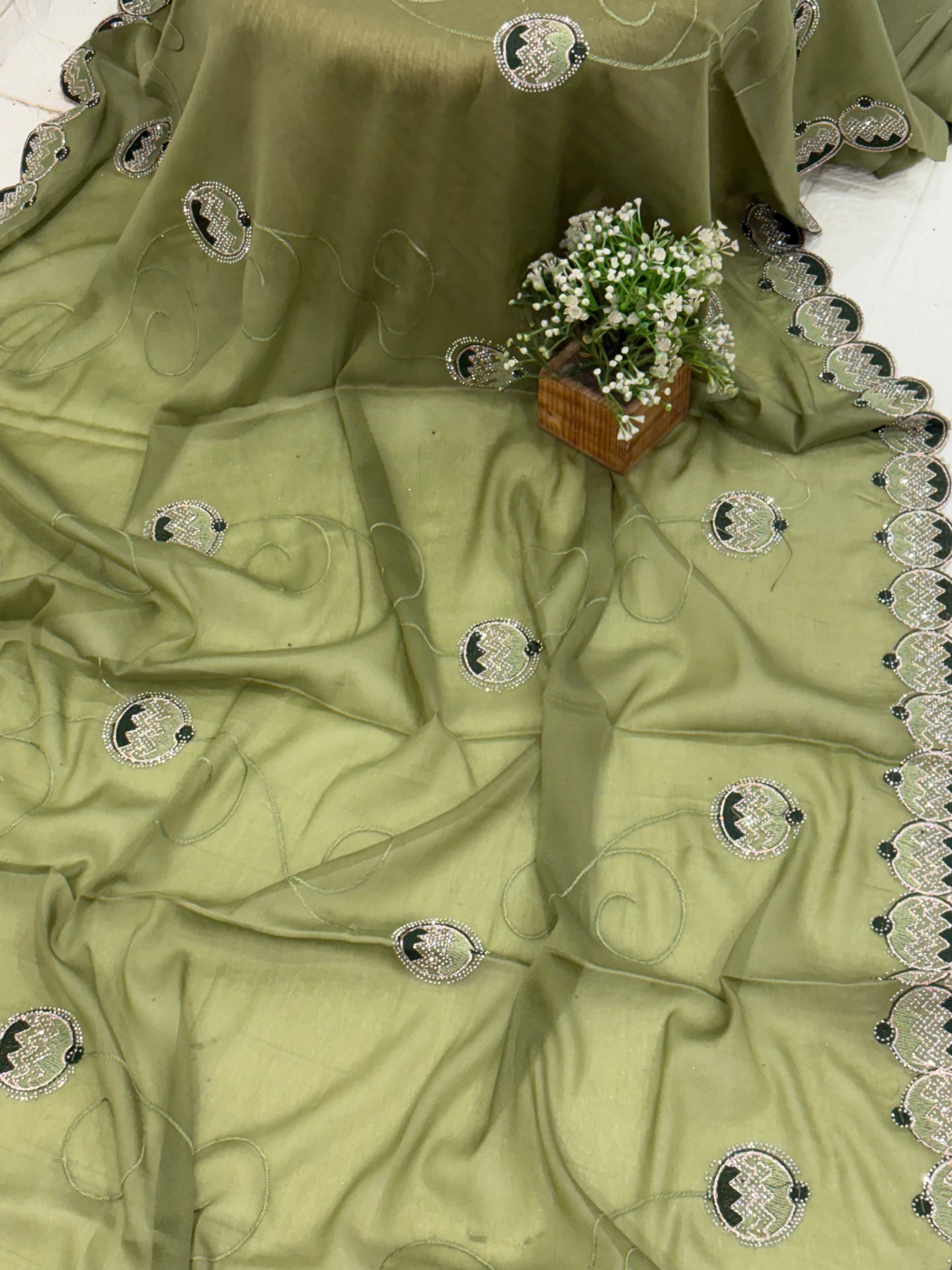 Saree georgette or organza and light mehndi green colour embroidered medallion butti and saree with scalloped border it is a sheer saree with scattered embroider and stonework