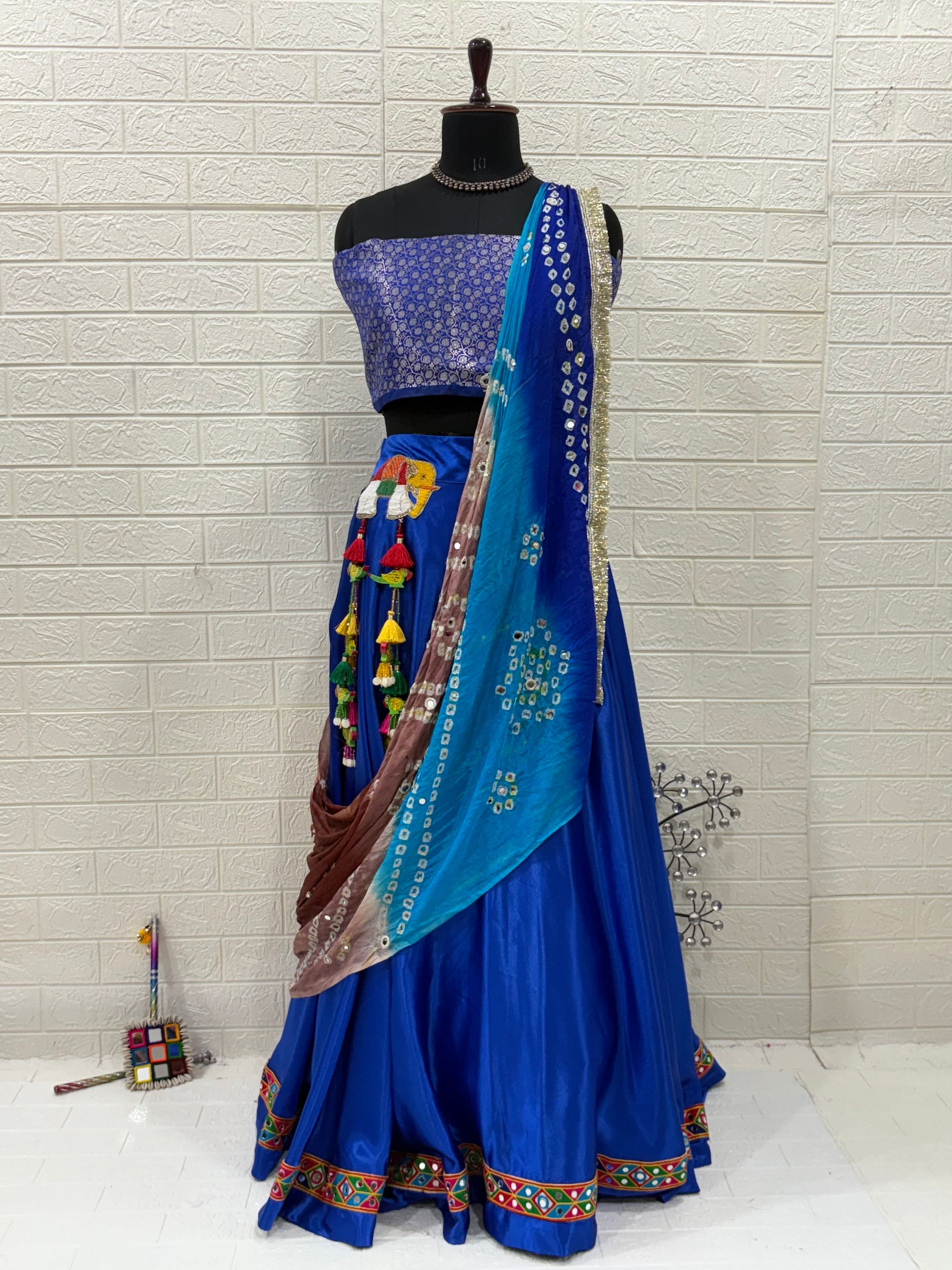 Name: Royal Blue Lehenga & Dupatta A vibrant royal blue crafted in soft pure synthetic satin Lehenga with patchwork,brocade blouse with mirror work Bandhni Dupatta and sequin lace, perfect for festive celebrations.