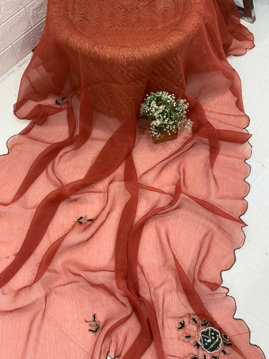 This fabric is a rust peach shimmer with embroiderd  organza with a soft shimmer, featuring delicate thread embroidery in Green and gold. The edges have a fine scallop finish, giving it a graceful drape.