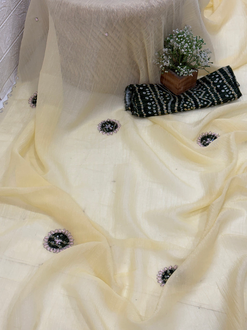 Light yellow crepe Saree with a sheer, lightweight fabric forest green Bandhani print blouse base embellished with sequins and embroidery butas.
