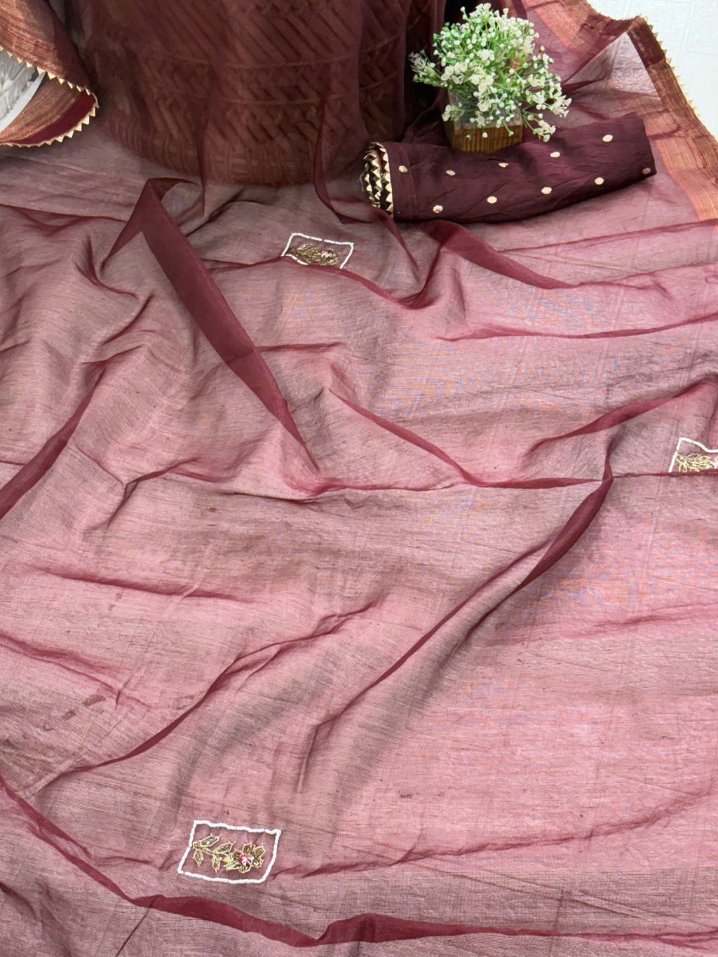 Name: Chanderi or Cotton Silk Saree Fabric The fine texture, sheen, and way the material is folded suggest a Chanderi or Cotton Silk Blend. The work is Zari Woven Stripes with Aari/Thread Embroidery motifs.