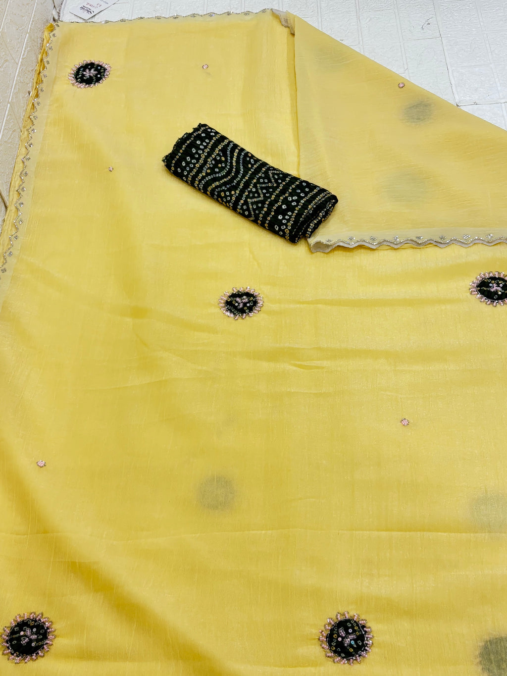 Light yellow crepe Saree with a sheer, lightweight fabric forest green Bandhani print blouse base embellished with sequins and embroidery butas.