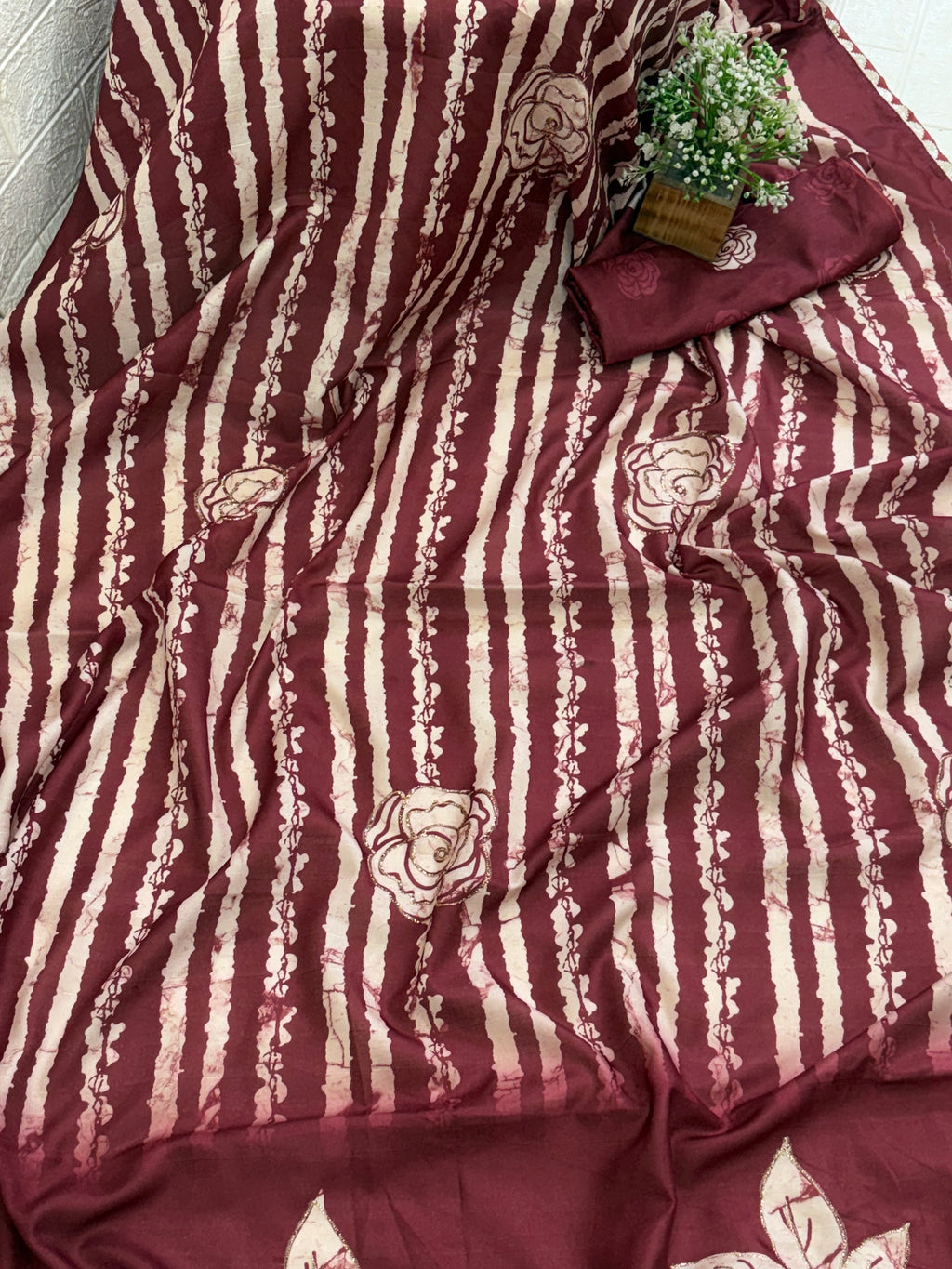Name: Batik Print Saree/Fabric
Fabric: Typically Cotton or Cotton Silk Blend, sometimes Crepe or Silk, featuring a maroon and off-white wax-resist (Batik) print with rose and stripe motifs.